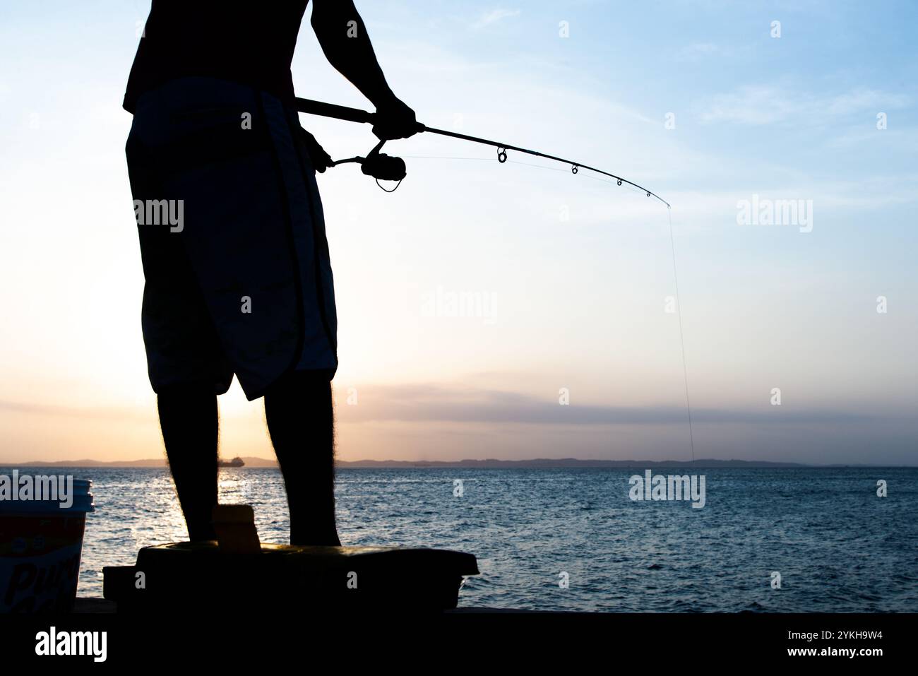 Salvador, Bahia, Brésil - 16 novembre 2019 : silhouette d'un homme pêcheur tenant une canne pendant le coucher du soleil dans la ville de Salvador, Bahia. Banque D'Images