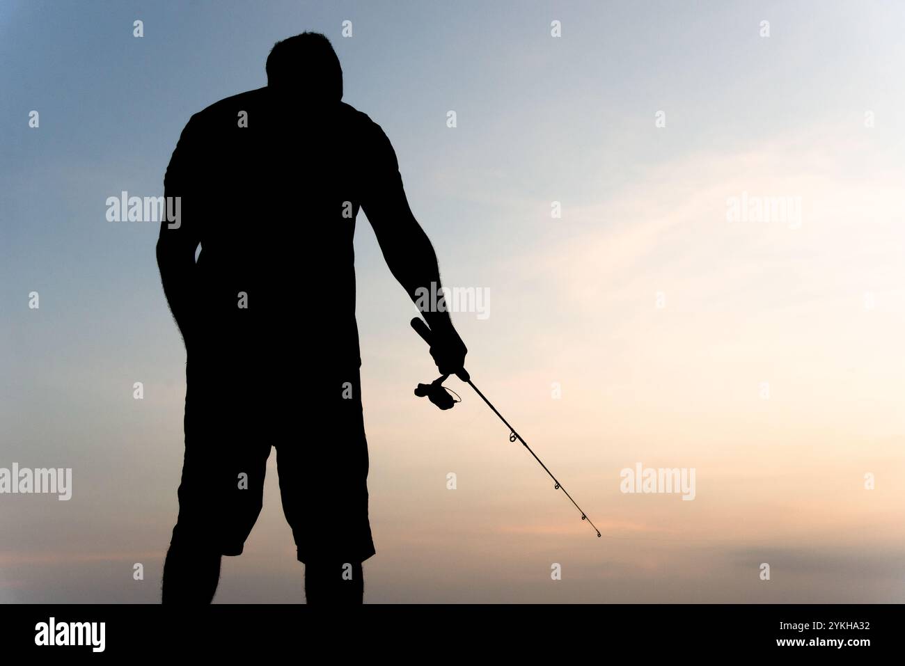 Salvador, Bahia, Brésil - 16 novembre 2019 : silhouette d'un homme pêcheur tenant une canne pendant le coucher du soleil dans la ville de Salvador, Bahia. Banque D'Images