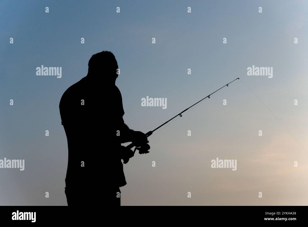 Salvador, Bahia, Brésil - 16 novembre 2019 : silhouette d'un homme pêcheur tenant une canne pendant le coucher du soleil dans la ville de Salvador, Bahia. Banque D'Images