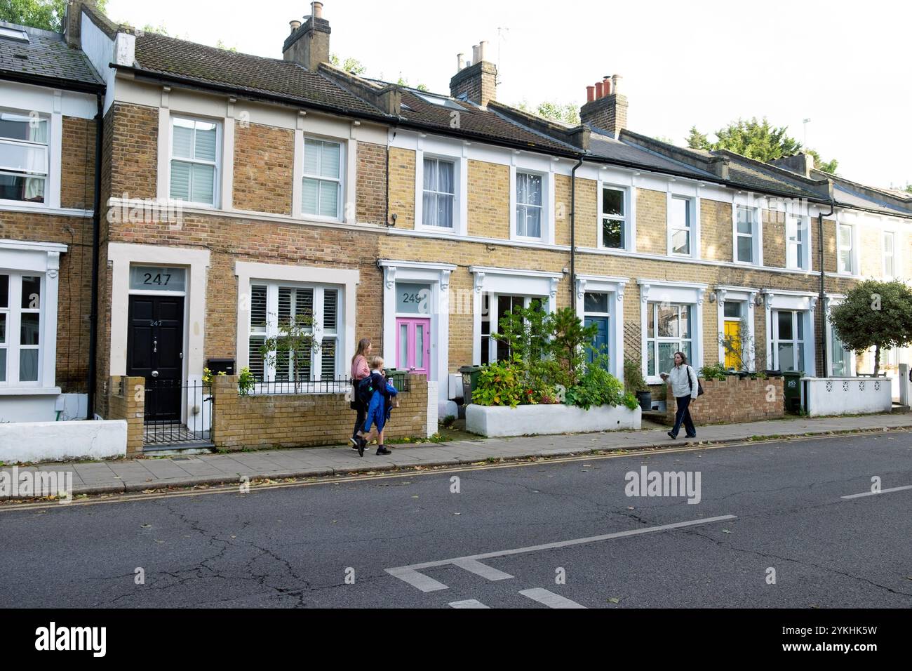 Les gens marchant devant la rangée de maisons mitoyennes à l'extérieur sur Railton Road dans le quartier de Brixton octobre 2024 Londres Angleterre Royaume-Uni KATHY DEWITT Banque D'Images