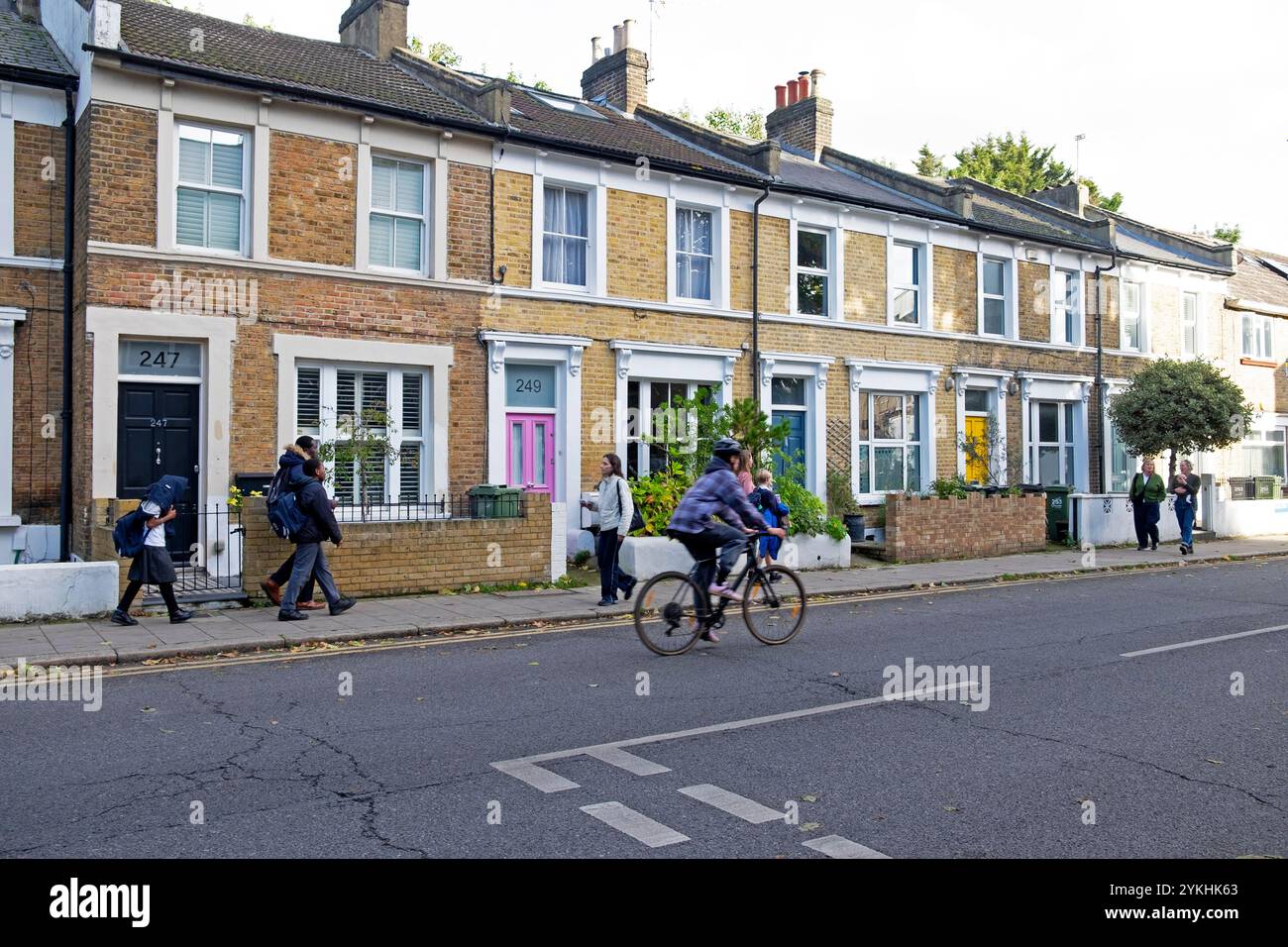 Les gens marchant devant la rangée de maisons mitoyennes à l'extérieur sur Railton Road dans le quartier de Brixton octobre 2024 Londres Angleterre Royaume-Uni KATHY DEWITT Banque D'Images