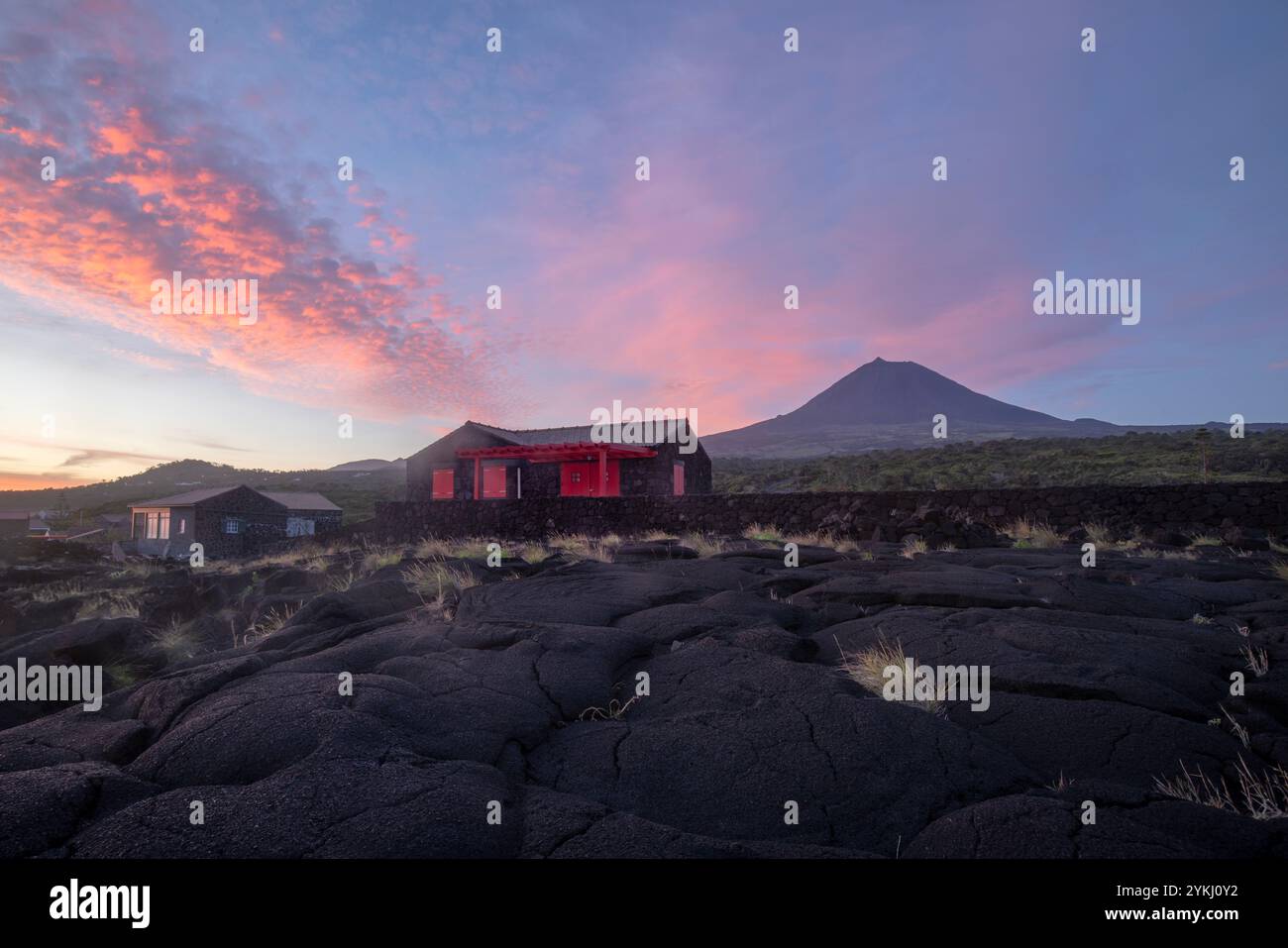 Cabrito, sur l'île de Pico aux Açores, dispose d'une zone de baignade en lave noire avec des maisons traditionnelles en pierre de lave surplombant le majestueux Mont Pico. Banque D'Images