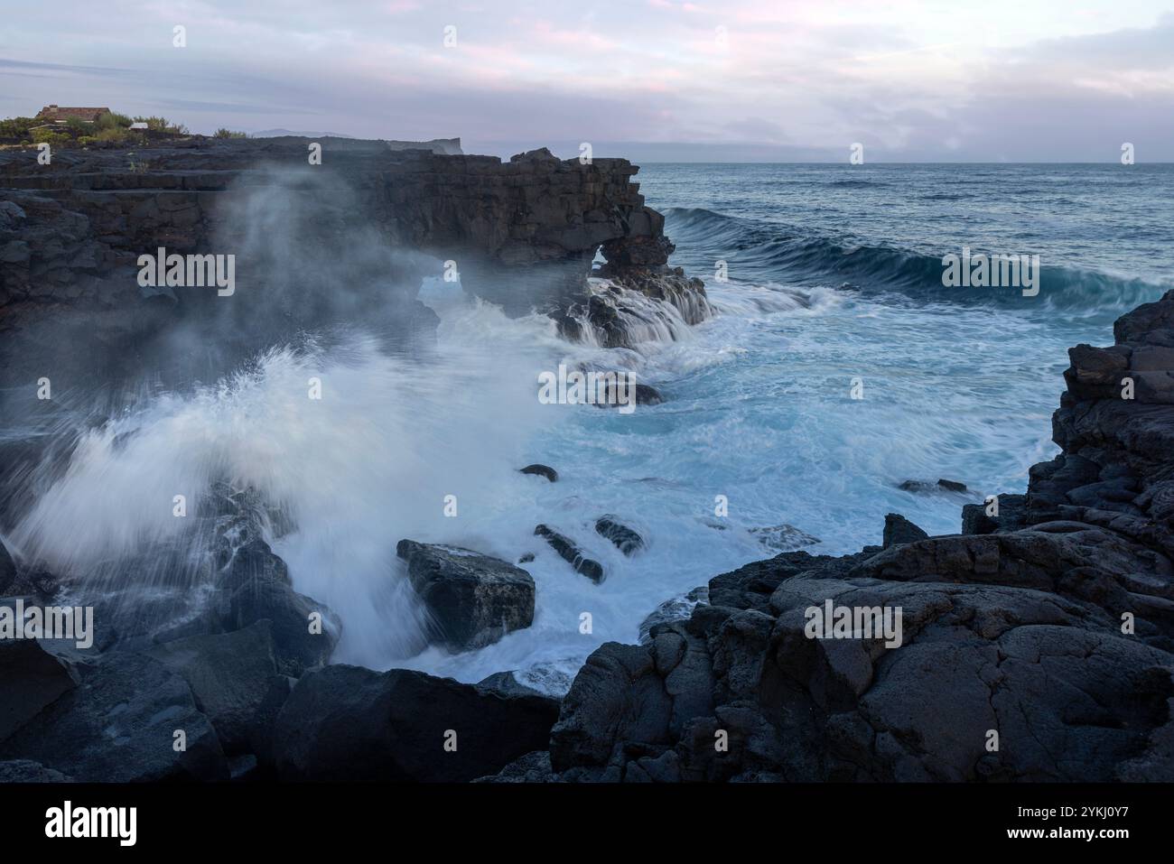Cabrito, sur l'île de Pico aux Açores, dispose d'une zone de baignade en lave noire avec des maisons traditionnelles en pierre de lave surplombant le majestueux Mont Pico. Banque D'Images