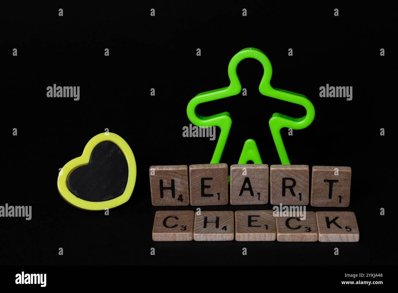 Figurine humaine en plastique pour enfants avec cœur jaune et lettres DE VÉRIFICATION DU CŒUR, sensibilisation à la Journée mondiale du cœur Banque D'Images