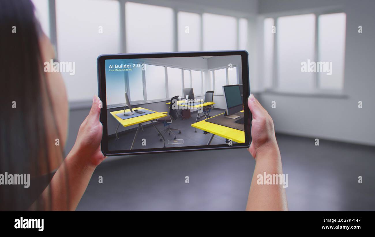 Designer asiatique utilise une tablette et un logiciel de design d'intérieur en réalité augmentée pour construire des bureaux. L'écran de la tablette montre la salle de balayage de l'application ai Builder, créant un design avec des objets de mobilier 3D. Banque D'Images