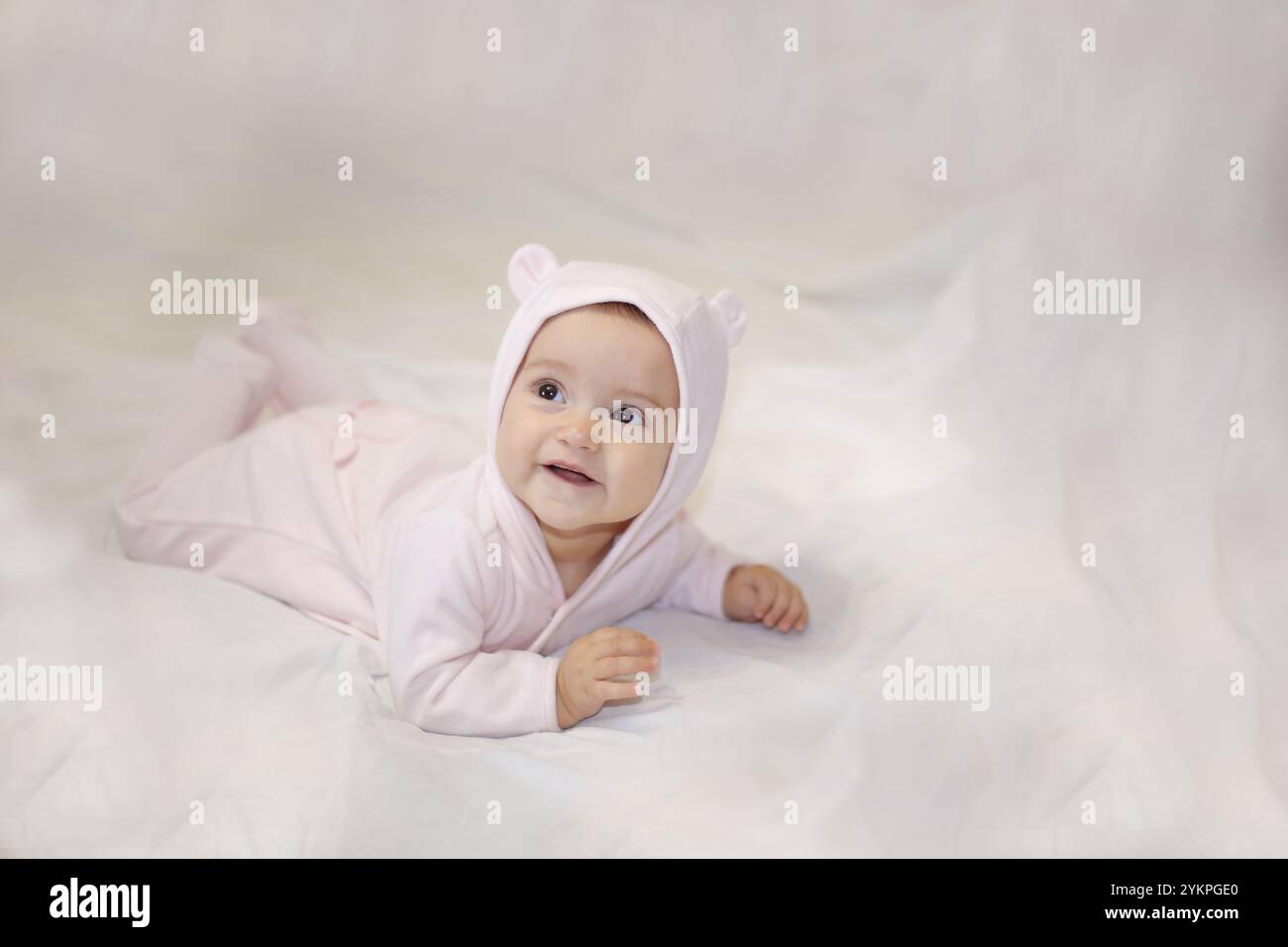 Enfant couché souriant dans un costume d'ours sur un fond clair Banque D'Images