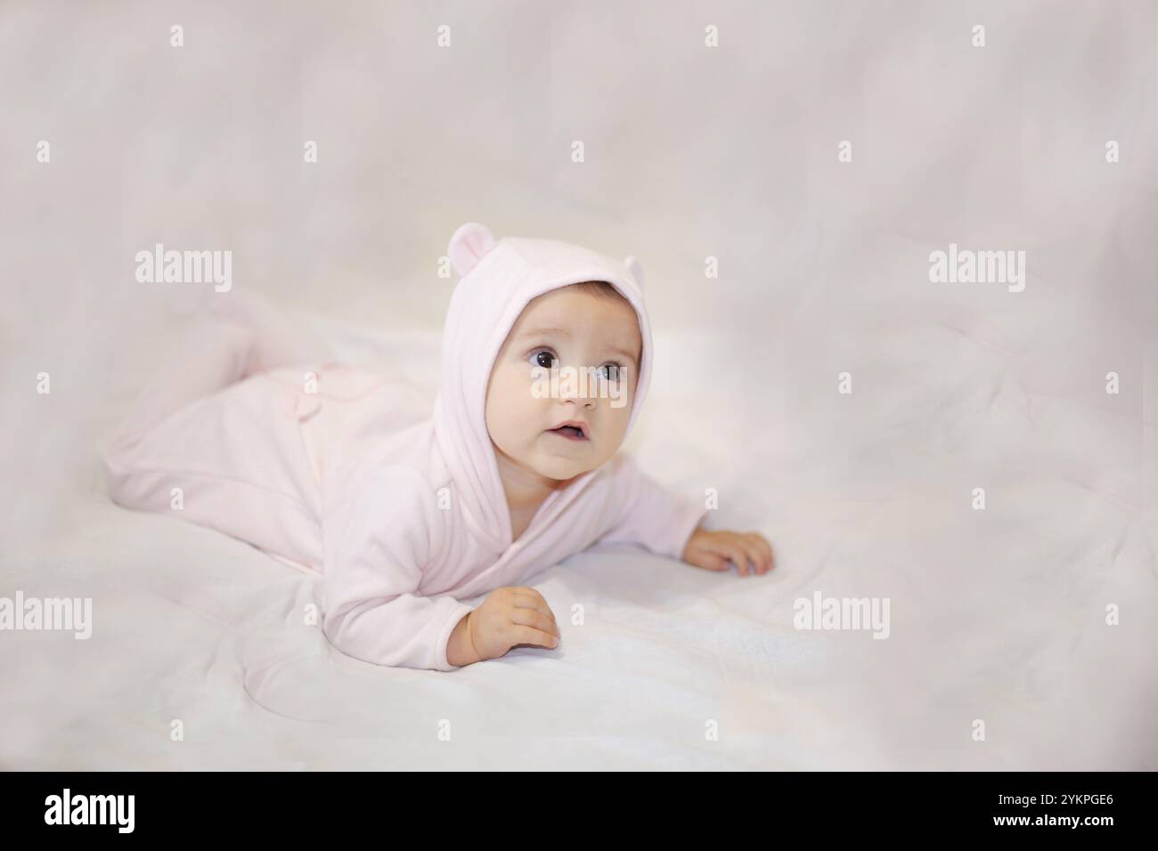 Un charmant petit bébé vêtu d'une jolie combinaison rose, rayonnant de joie tout en étant allongé sur une couverture douillette et douce Banque D'Images