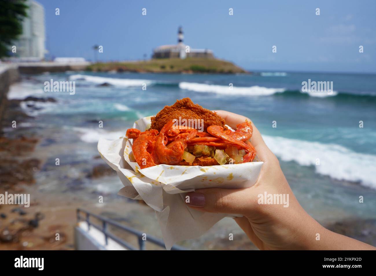 Plat traditionnel Acaraje et cuisine de rue du nord-est du Brésil avec le phare de Farol da Barra et la baie de tous les Saints en arrière-plan, Salvador de Bah Banque D'Images