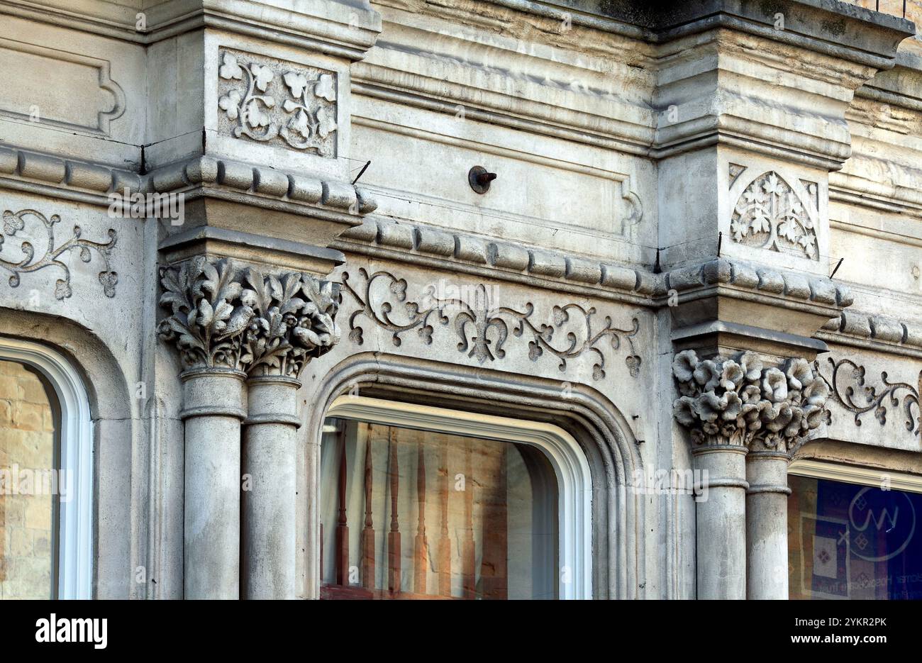 Deux des nombreux chapiteaux sculptés au rez-de-chaussée d'un bâtiment du XIXe siècle dans South Street, Sherborne, Dorset. Banque D'Images