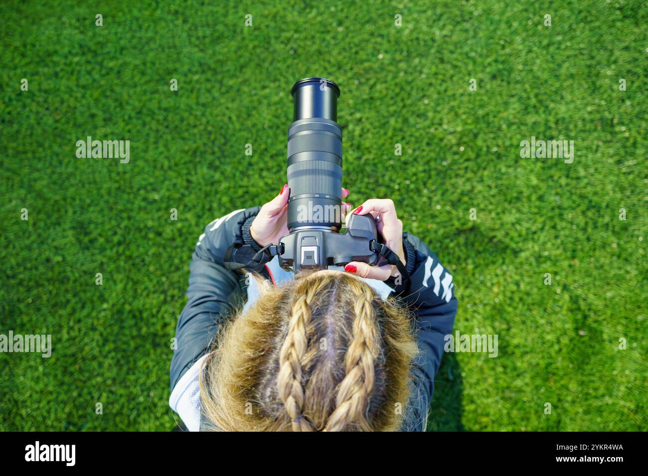Vue aérienne d'une photographe sportive d'âge moyen prenant des photos sur un terrain de football pendant un match au crépuscule Banque D'Images