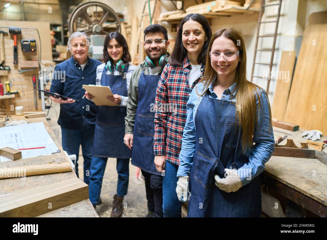Un groupe de charpentiers diversifiés, jeunes et plus âgés, collaborent avec enthousiasme dans un chantier forestier. L'image met en évidence le travail d'équipe, le développement des compétences, un Banque D'Images