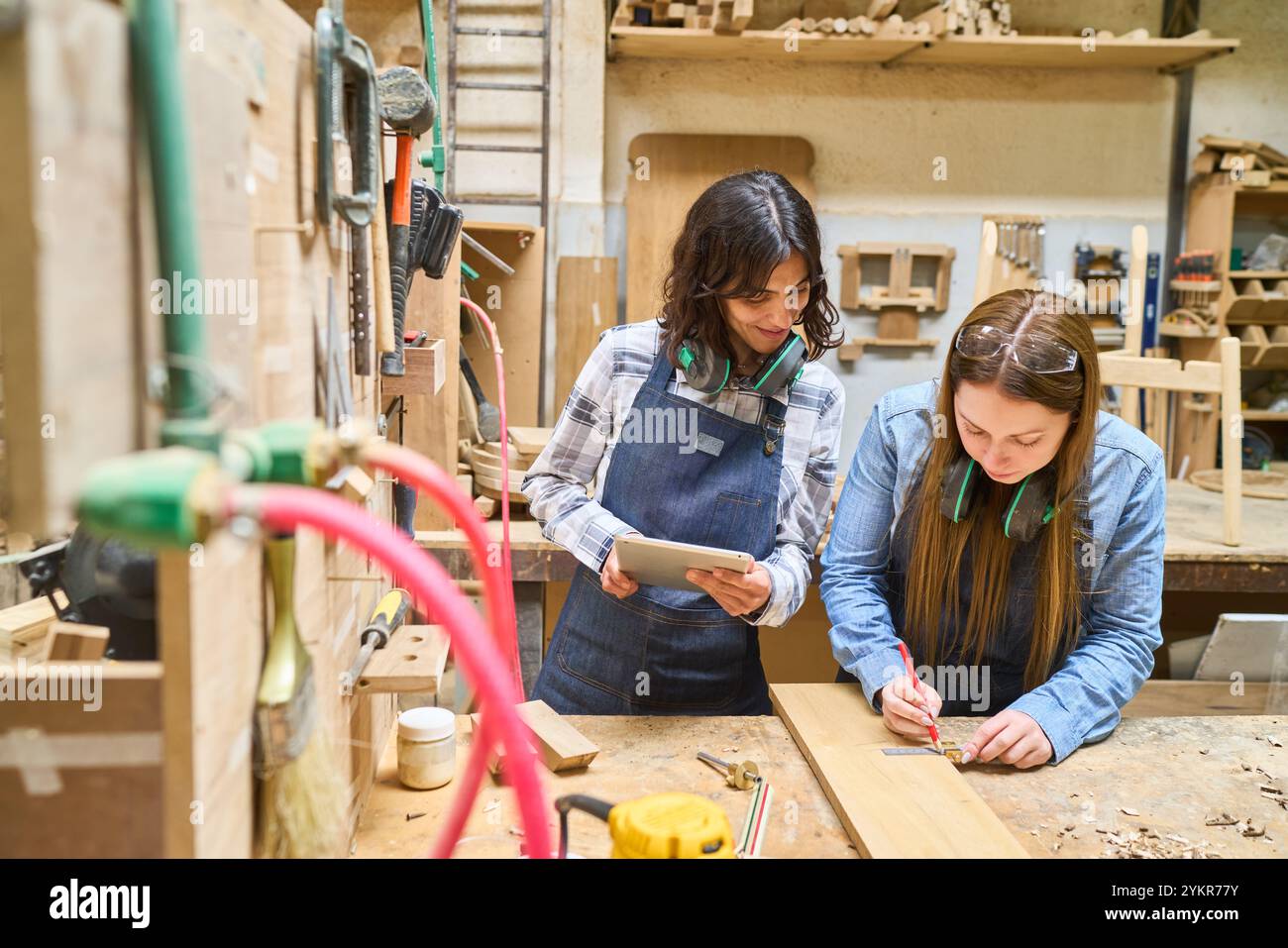 Deux personnes travaillent dans un chantier forestier, se concentrant sur le travail d'équipe et le développement des compétences. L'un est engagé dans des boiseries précises tandis que l'autre fournit des conseils et Banque D'Images