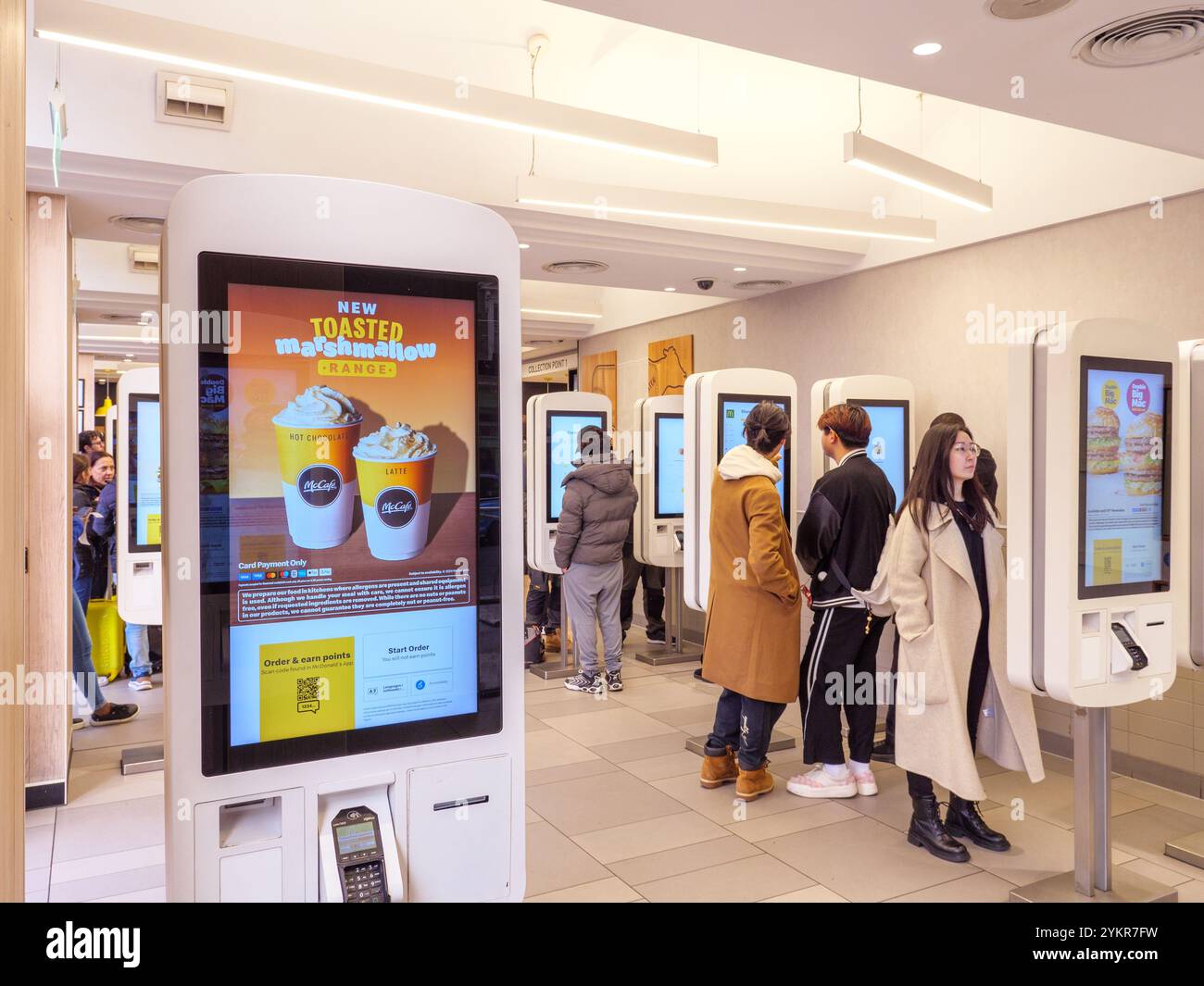 Les gens qui commandent leur nourriture à l'aide de terminaux de commande à écran tactile à l'intérieur d'un restaurant McDonald's, au Royaume-Uni Banque D'Images