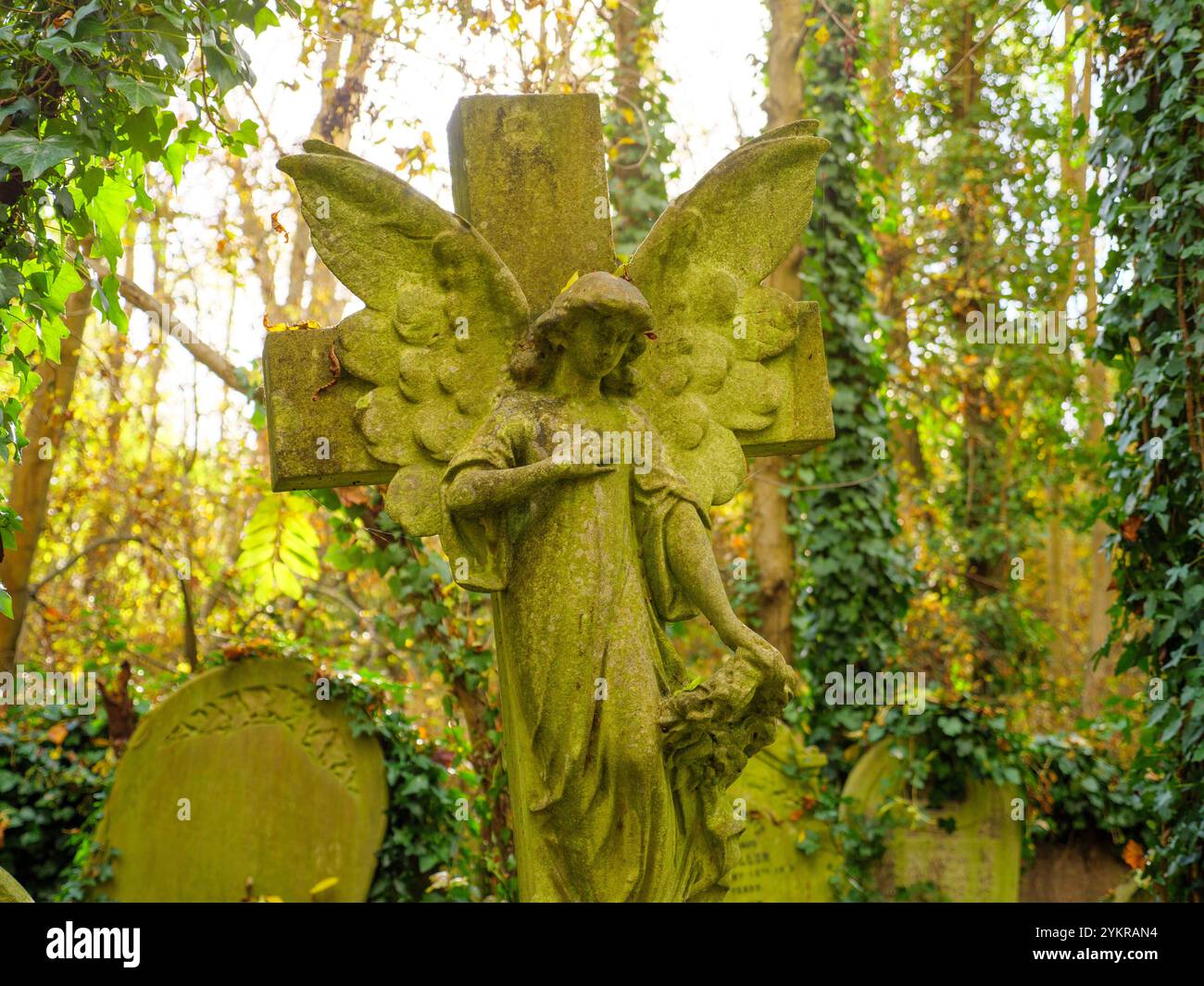 Ange en pierre sur la croix d'une pierre tombale d'une tombe dans le cimetière d'Abney Park, Hackney, Londres, Royaume-Uni Banque D'Images