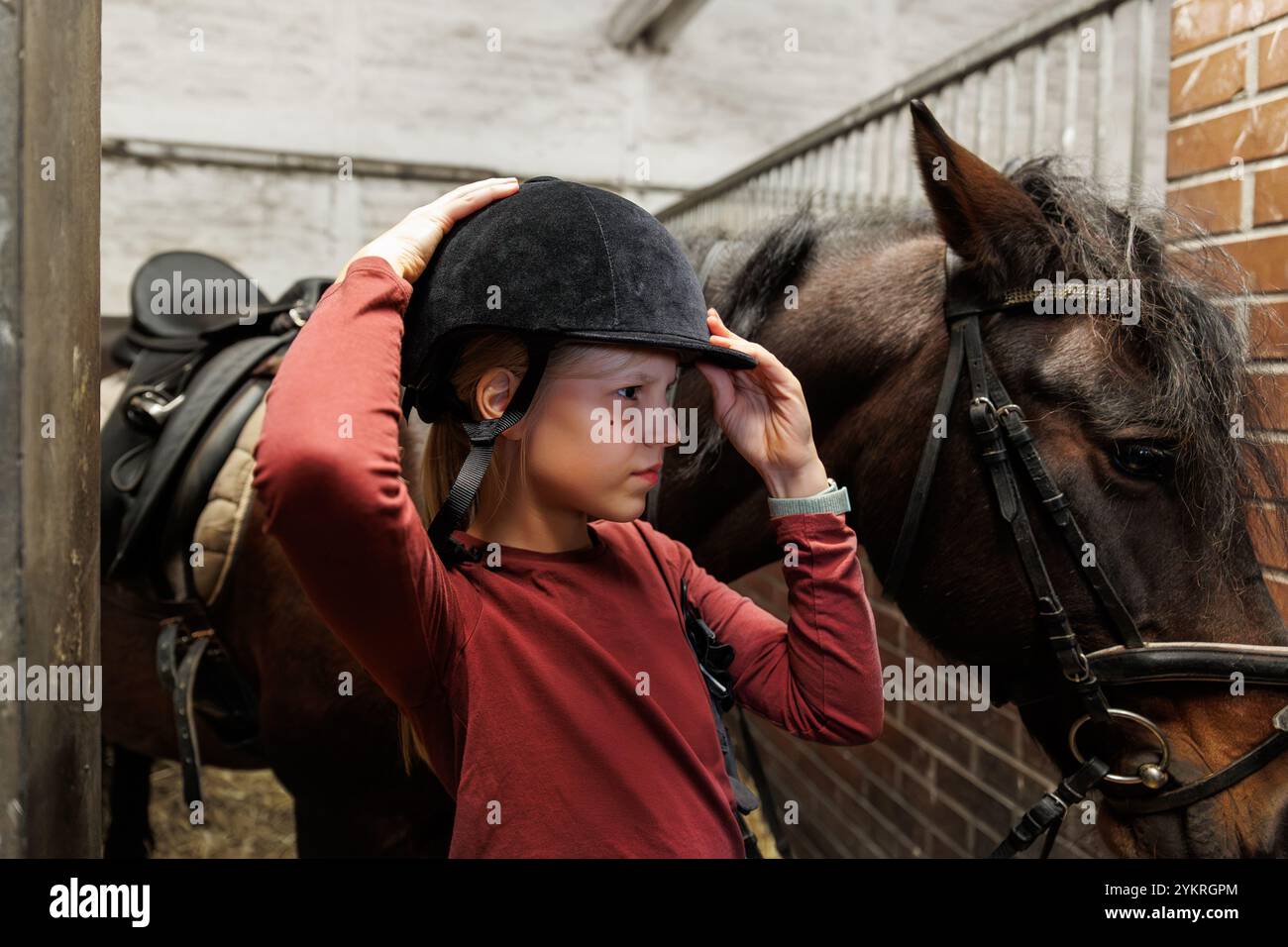 Jeune petite adolescente enfant fille de nettoyage de toilettage châtaigne cheval dos brosse cheveux cheval outil à ranch stable. Balade à cheval école vie de ferme. Mignon petit Banque D'Images