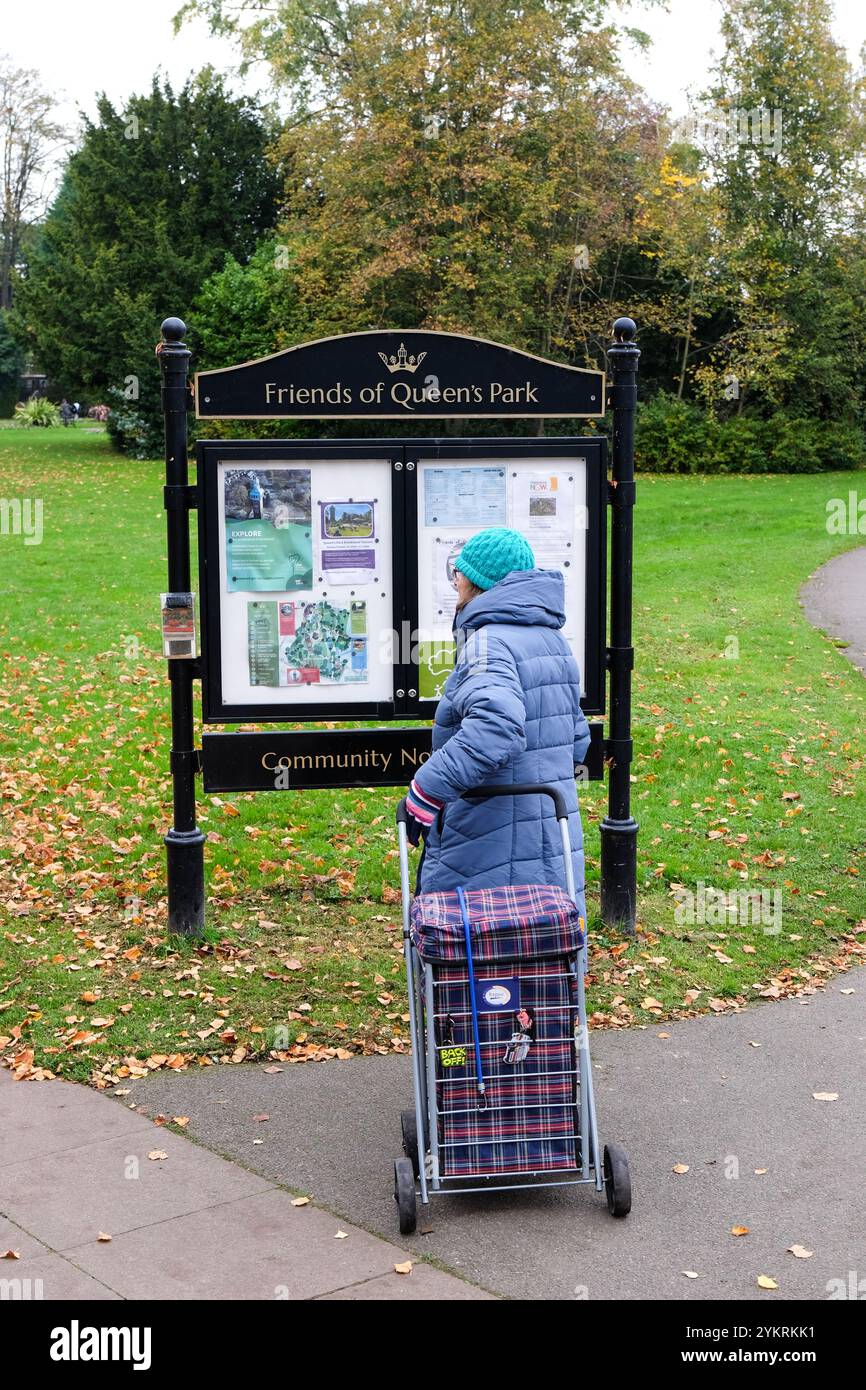 femme regardant le panneau d'affichage dans queens park loughborough Banque D'Images