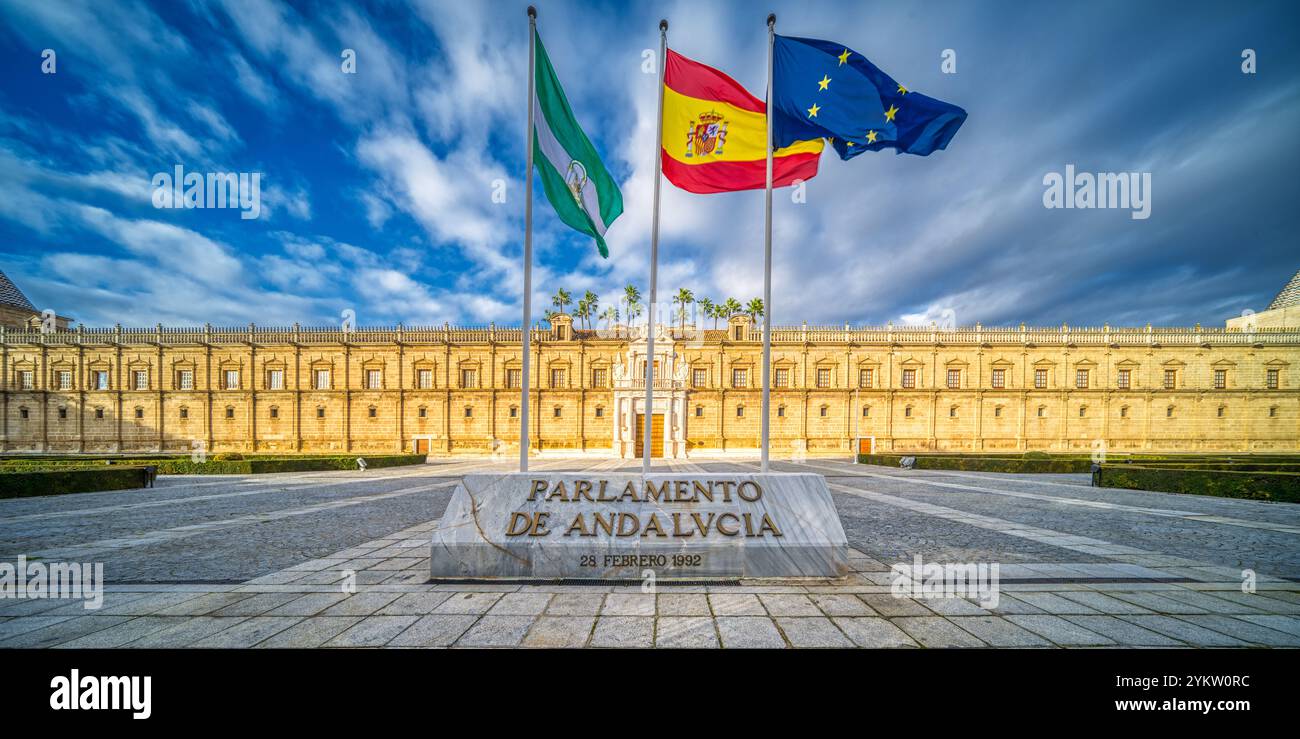 L'image capture l'emblématique Hospital de las Cinco Llagas, aujourd'hui le Parlement d'Andalousie, à Séville. Trois drapeaux ondulent bien en vue sous un SK vif Banque D'Images