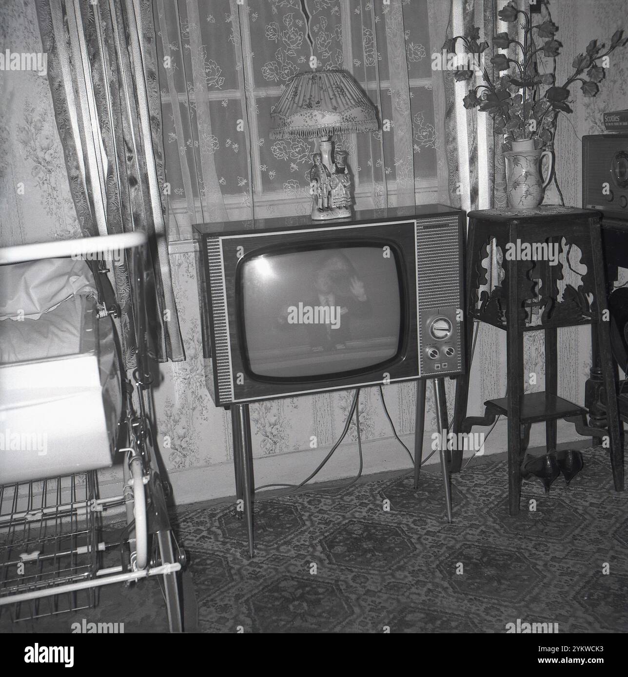 Vers le début des années 1960, historique, un poste de télévision Defiant de l'époque debout dans une salle de devant, car construit en autocar à côté d'elle. Radio dans le coin. Rideaux de filet dans la fenêtre. « Defiant » était une marque établie par la Co-Op. Les marques de télévision bien connues d’Ekco, Bush, etc. Utilisaient des concessionnaires pour vendre et entretenir leurs téléviseurs, escompter le prix n’était pas autorisé et la Co-op a donc demandé à Plessey de construire ses radios et téléviseurs, en utilisant le nom Defiant pour démontrer ce qu’ils pensaient des «grands» noms de l’industrie. Banque D'Images