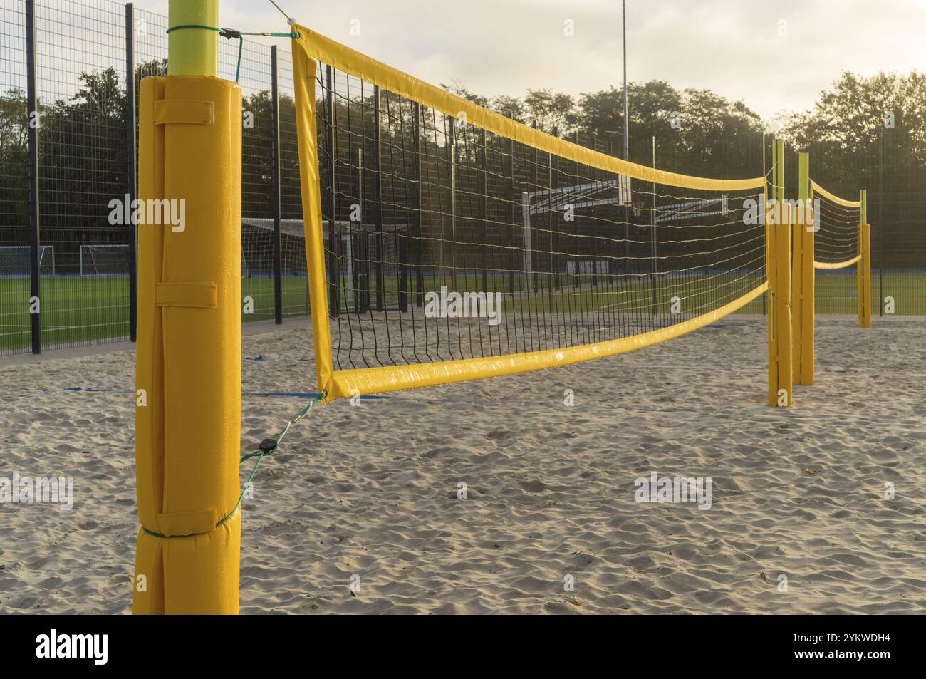 Filet de volley jaune s'étendant sur un terrain de Beach volley de sable par une journée ensoleillée Banque D'Images