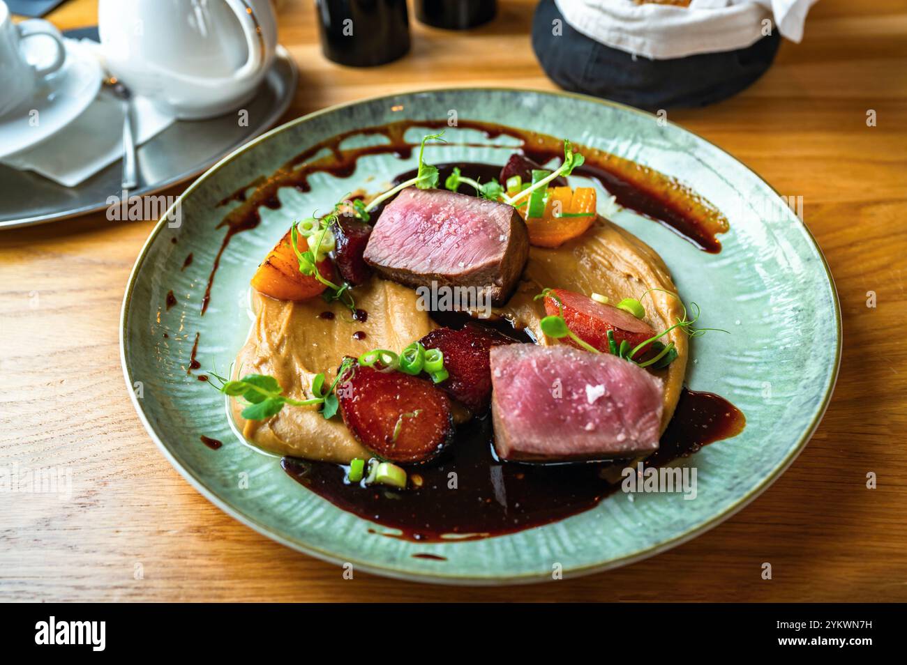 Morceau de viande de canard avec betterave cuite au four sur purée de châtaigniers avec sauce et feuille de pois germée sur une assiette décorative sur la table du restaurant. Festive. Martin' Banque D'Images