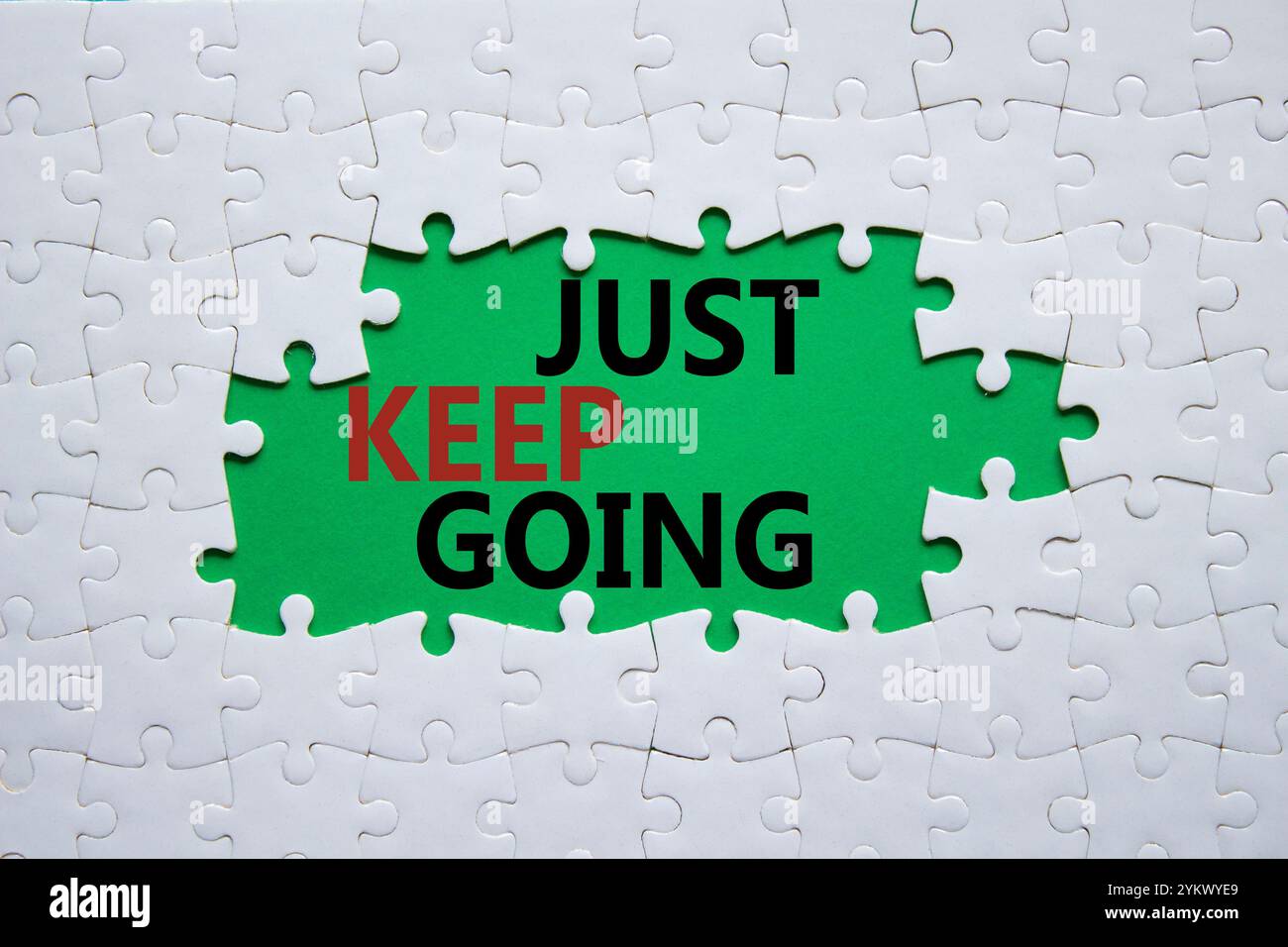 Symbole « continuez à aller ». Puzzle blanc avec des mots juste continuer. Beau fond vert. Business and Just Keep Go concept. Copier l'espace. Banque D'Images