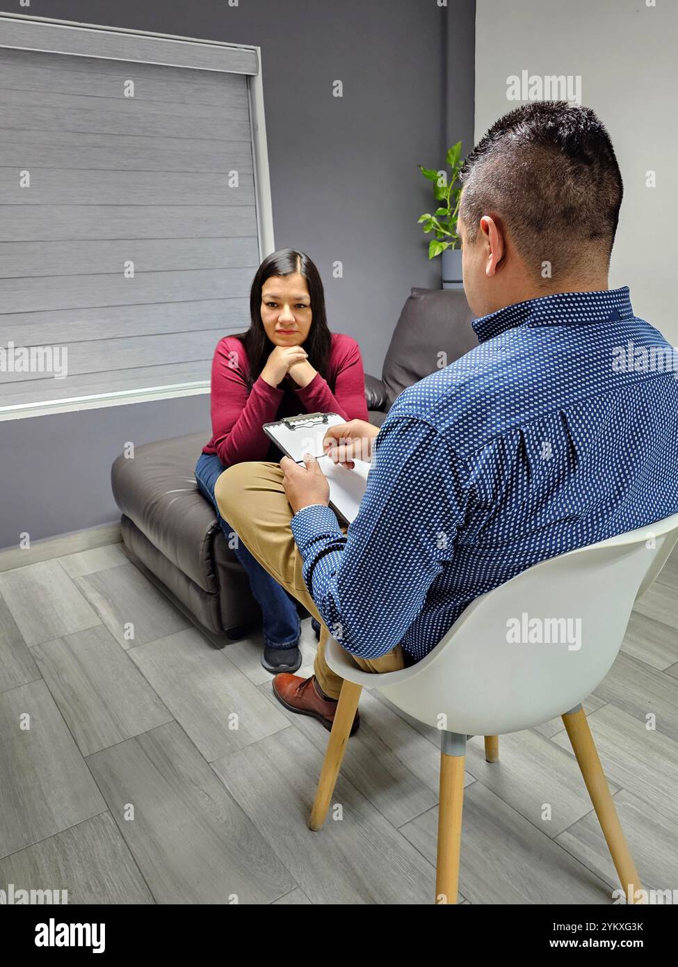 Psychologue masculin à la peau foncée donne une thérapie à une femme adulte latine écoutant le travail de santé mentale de son patient pour l'anxiété et la dépression Banque D'Images