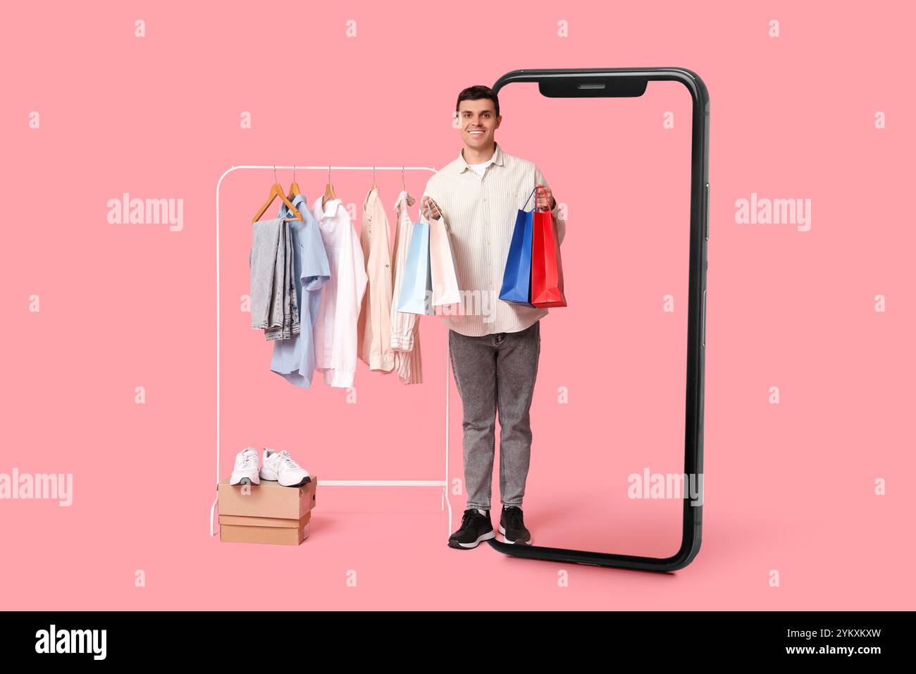 Grand téléphone portable et jeune homme avec des sacs à provisions et des vêtements élégants sur cintre sur fond rose Banque D'Images