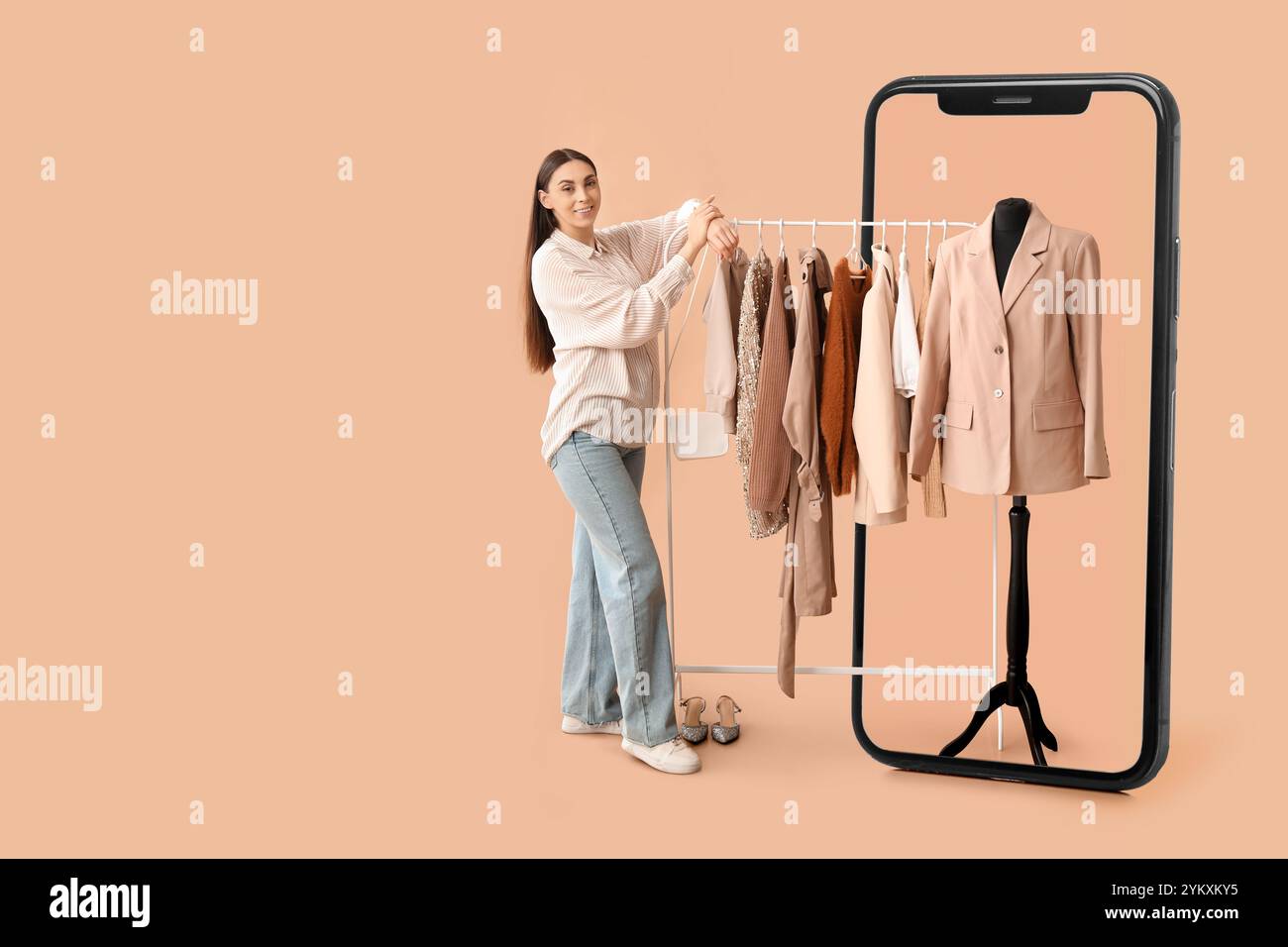 Grand téléphone portable et jeune femme avec des vêtements élégants sur cintre sur fond beige Banque D'Images