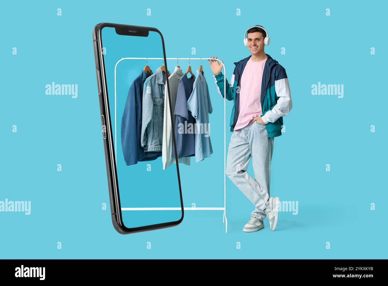 Grand téléphone portable et jeune homme avec des vêtements élégants sur cintre sur fond bleu Banque D'Images
