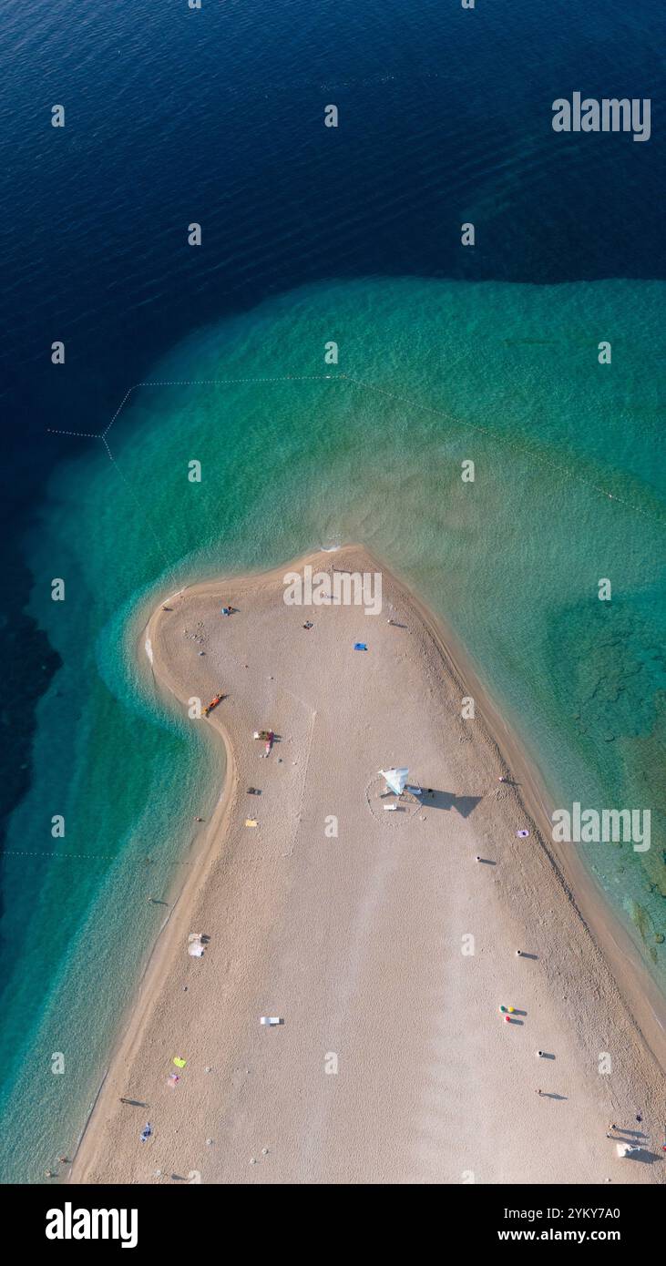 À Brac Island, les baigneurs profitent d'une journée sereine sur la plage de sable, embrassée par des eaux turquoises cristallines. Le paysage animé invite à la détente et à l'aventure, Zlatni Rat Beach Croatie Banque D'Images