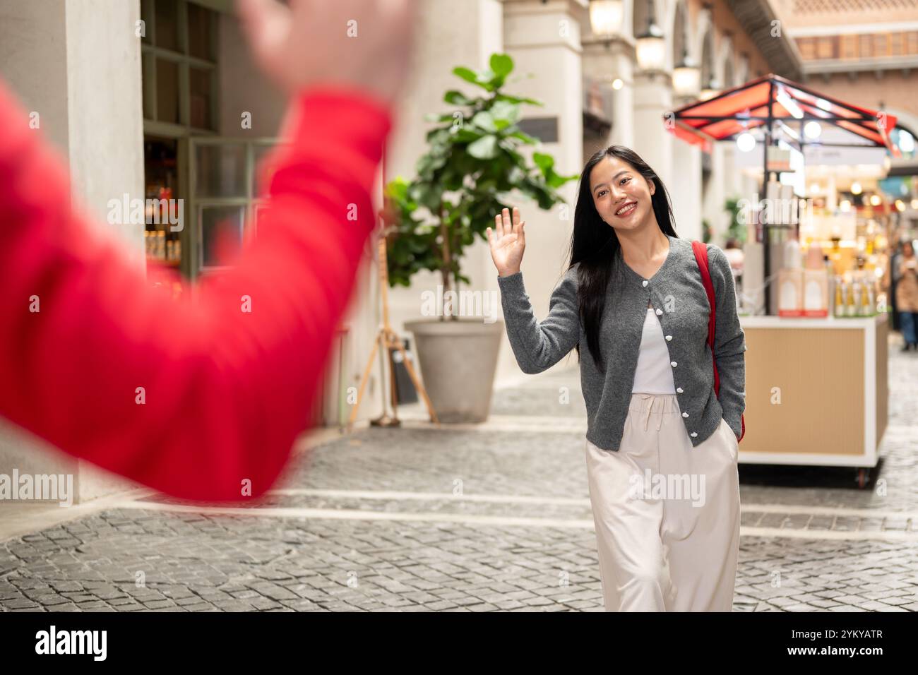 Une femme asiatique heureuse et amicale fait signe à son amie pour lui dire bonjour, après une rencontre inattendue tout en se promenant et en faisant du shopping dans la ville. les gens et la vie Banque D'Images