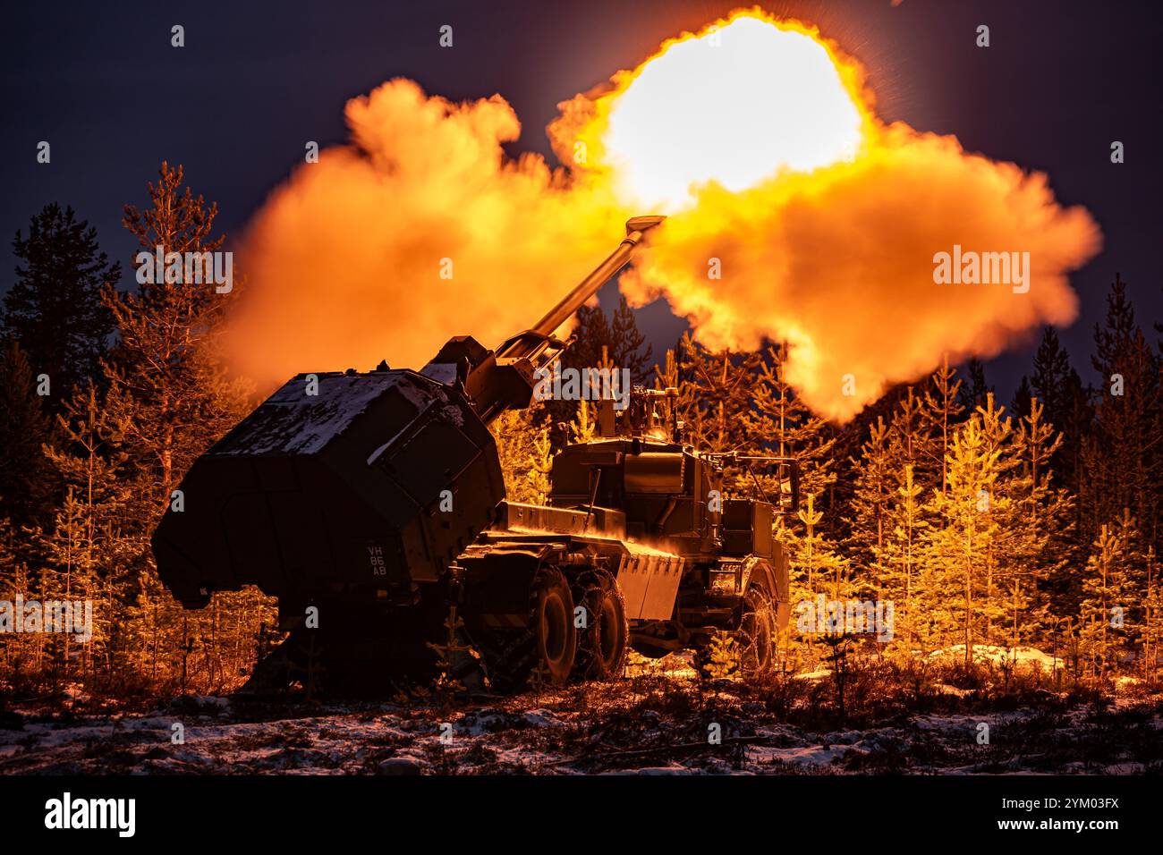 Un éclair de museau illumine les pins alors que le nouveau canon Archer Mobile Howitzer de l'armée britannique tire, alors que les soldats de l'armée britannique prennent part à l'entraînement près de Rovaniemi dans le cercle arctique, en Finlande. Date de la photo : mardi 19 novembre 2024. Banque D'Images