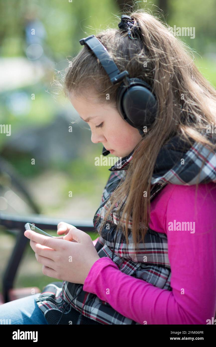 fille écouter de la musique dans des écouteurs noirs en plein air Banque D'Images