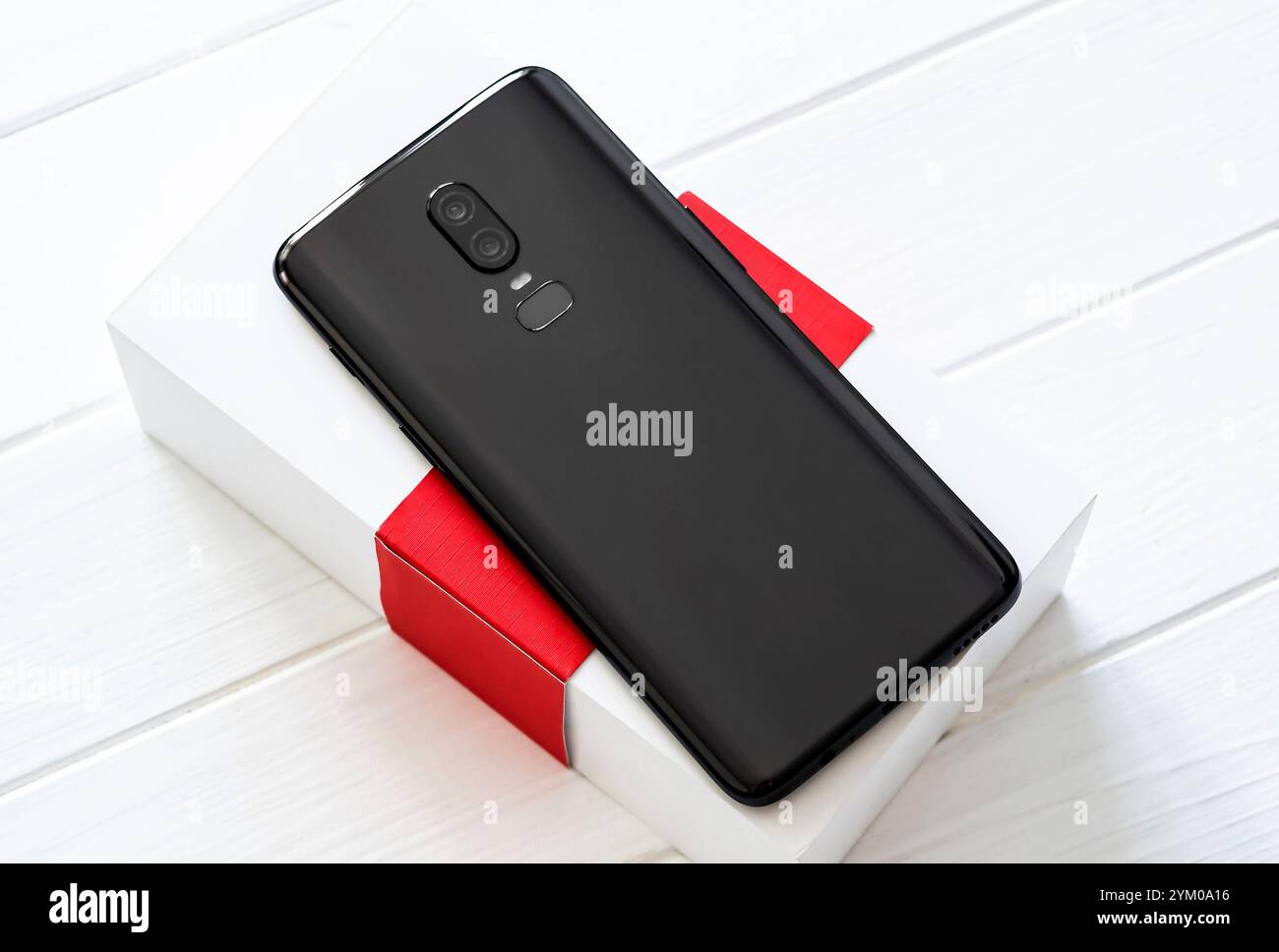 Smartphone moderne noir avec une boîte blanche sur la table en bois blanc Banque D'Images