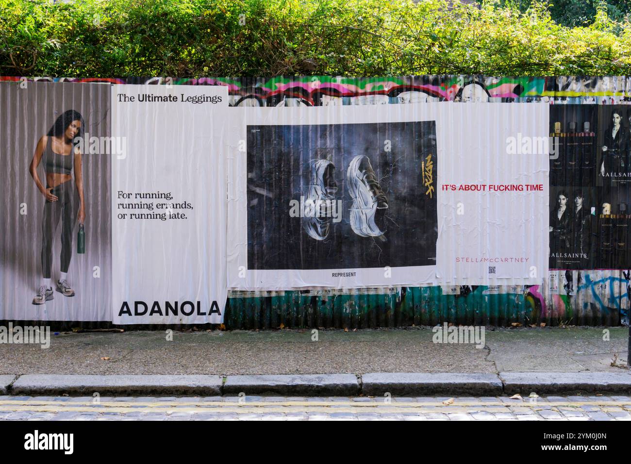 Affiches publicitaires collées sur une clôture en fer ondulé en vert Bethnal. Banque D'Images