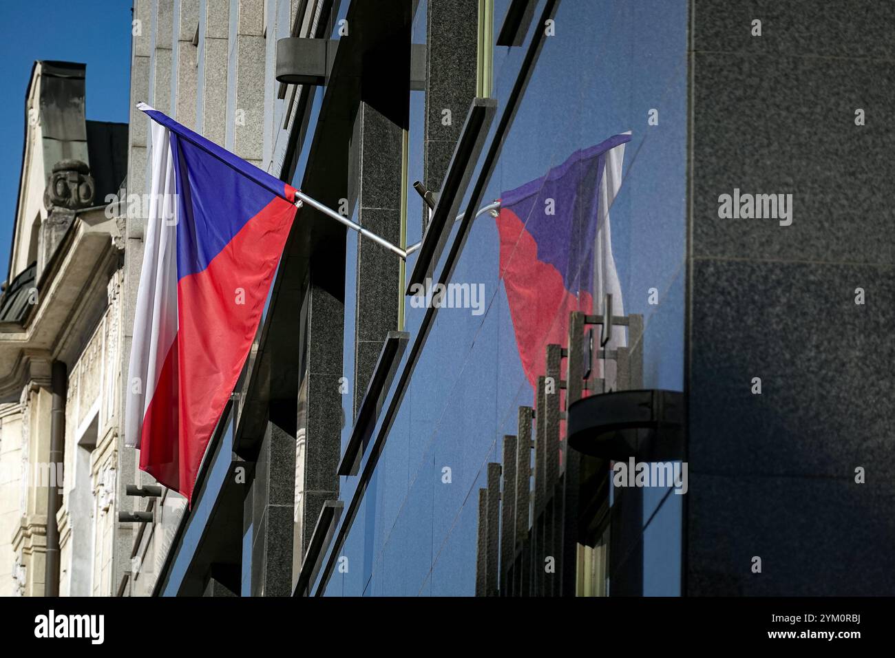 Drapeau national tchèque agitant sur un bâtiment moderne reflété sur un mur de marbre noir Banque D'Images