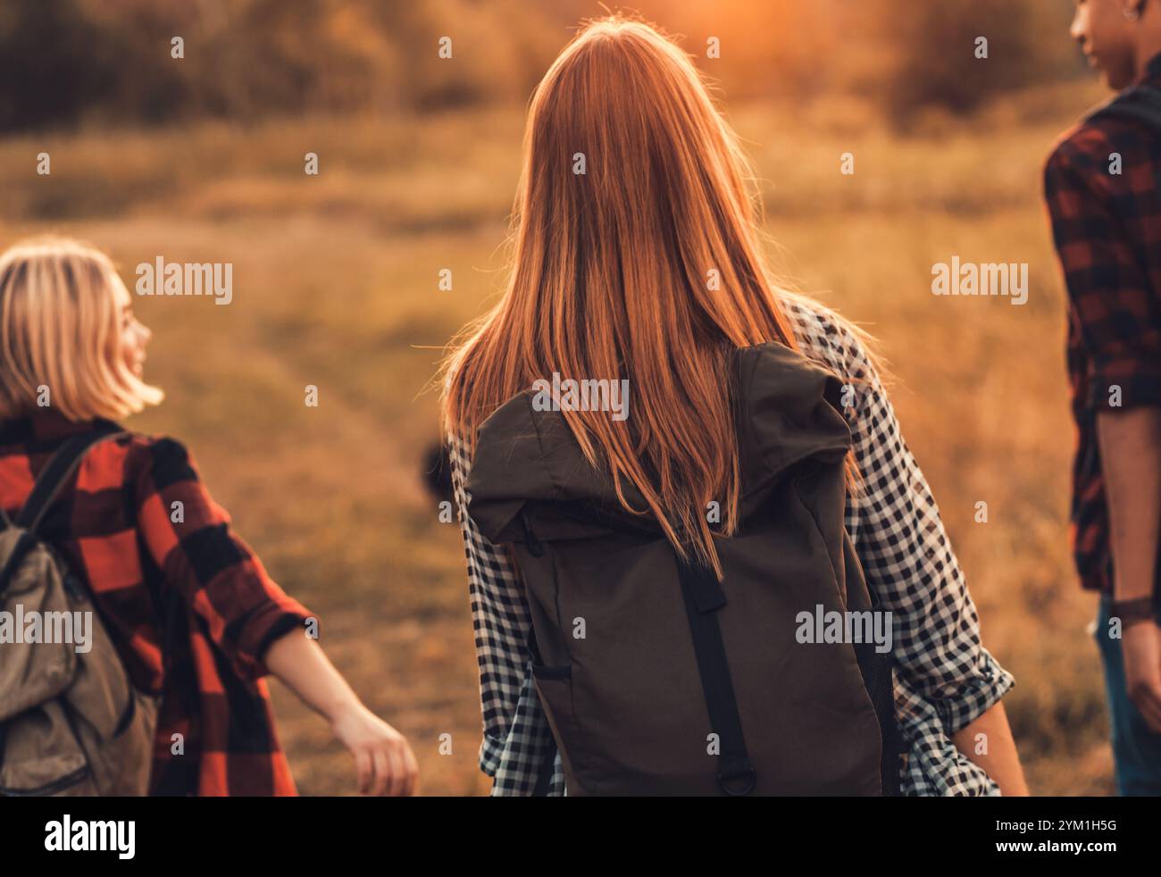 Groupe de quatre amis randonnant à travers la campagne ensemble au coucher du soleil. Banque D'Images