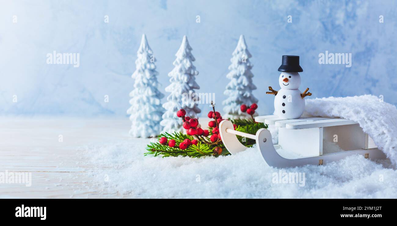 Décoration d'hiver, bonhomme de neige sur traîneau dans le paysage enneigé Banque D'Images