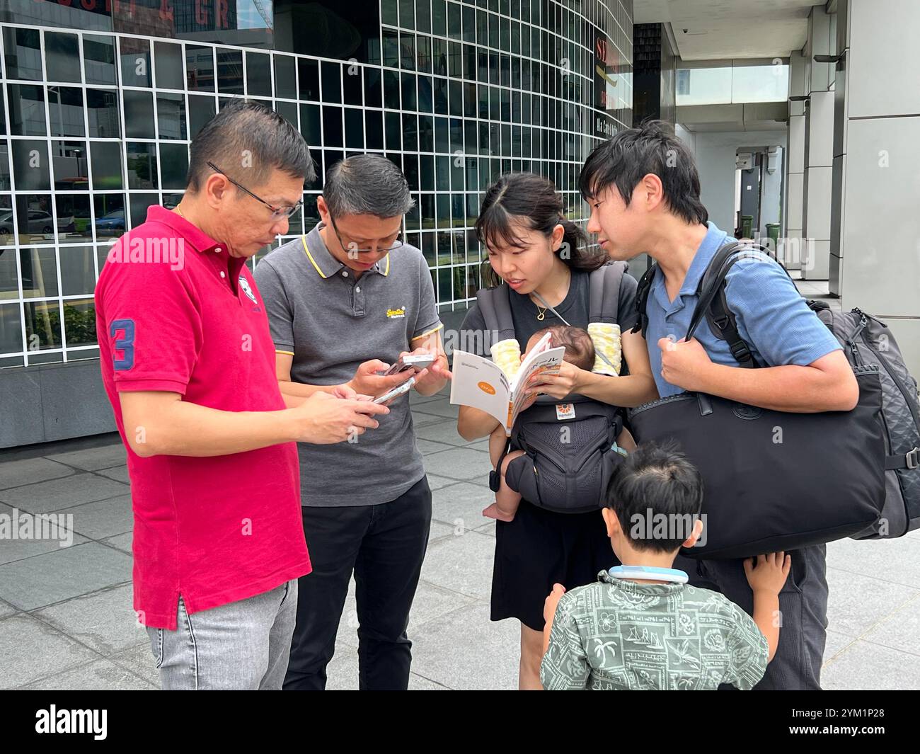 Famille japonaise demandant aux hommes singapouriens de la direction dans la rue. Les gentils messieurs sortirent rapidement leurs smartphones pour faire une recherche. Singapour. Banque D'Images