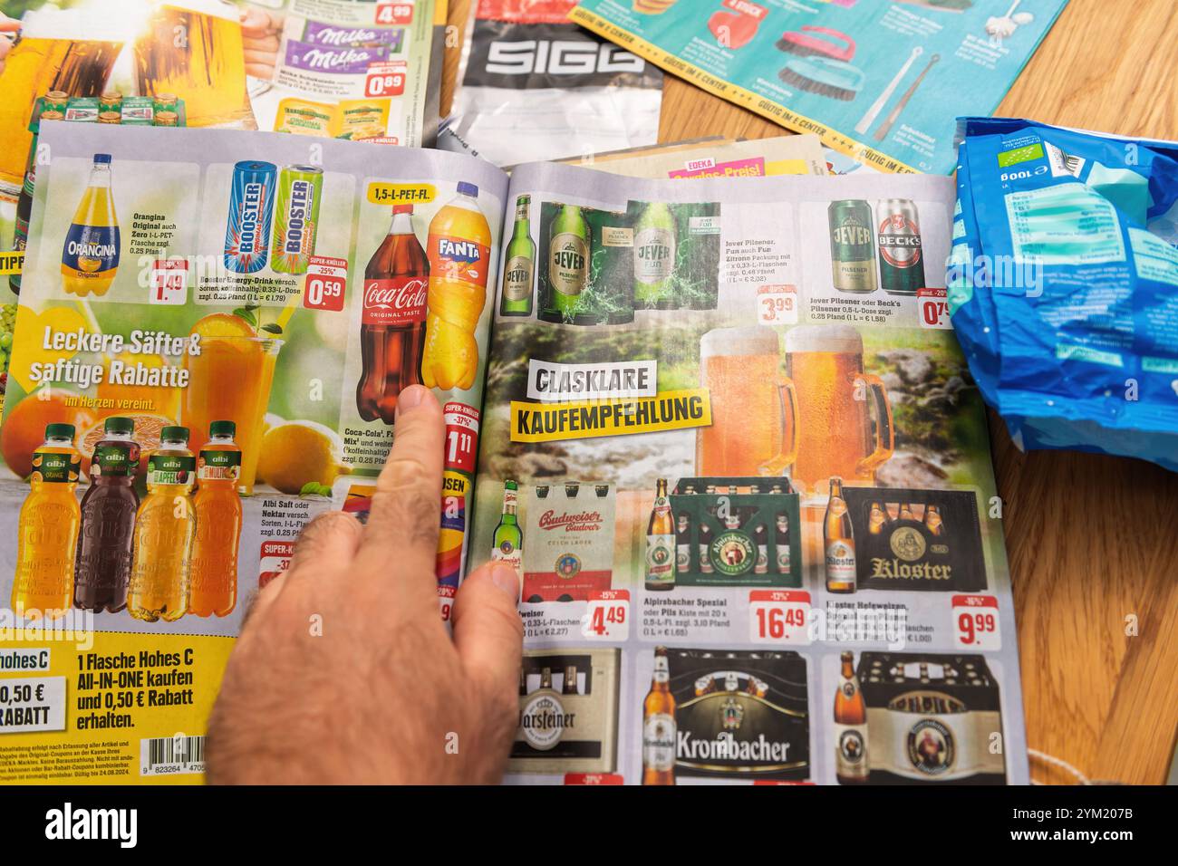 Francfort, Allemagne - 22 août 2024 : pointage de la main sur un dépliant allemand de boissons gazeuses, jus de fruits et bières, avec des réductions et des offres promotionnelles mises en valeur dans un agencement coloré Banque D'Images