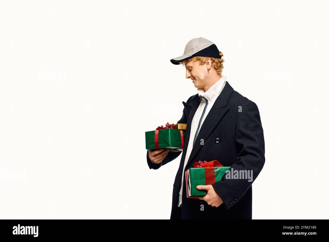 Habillé pour l'esprit des fêtes, un homme présente une mode unique avec des cadeaux de Noël à la main. Banque D'Images