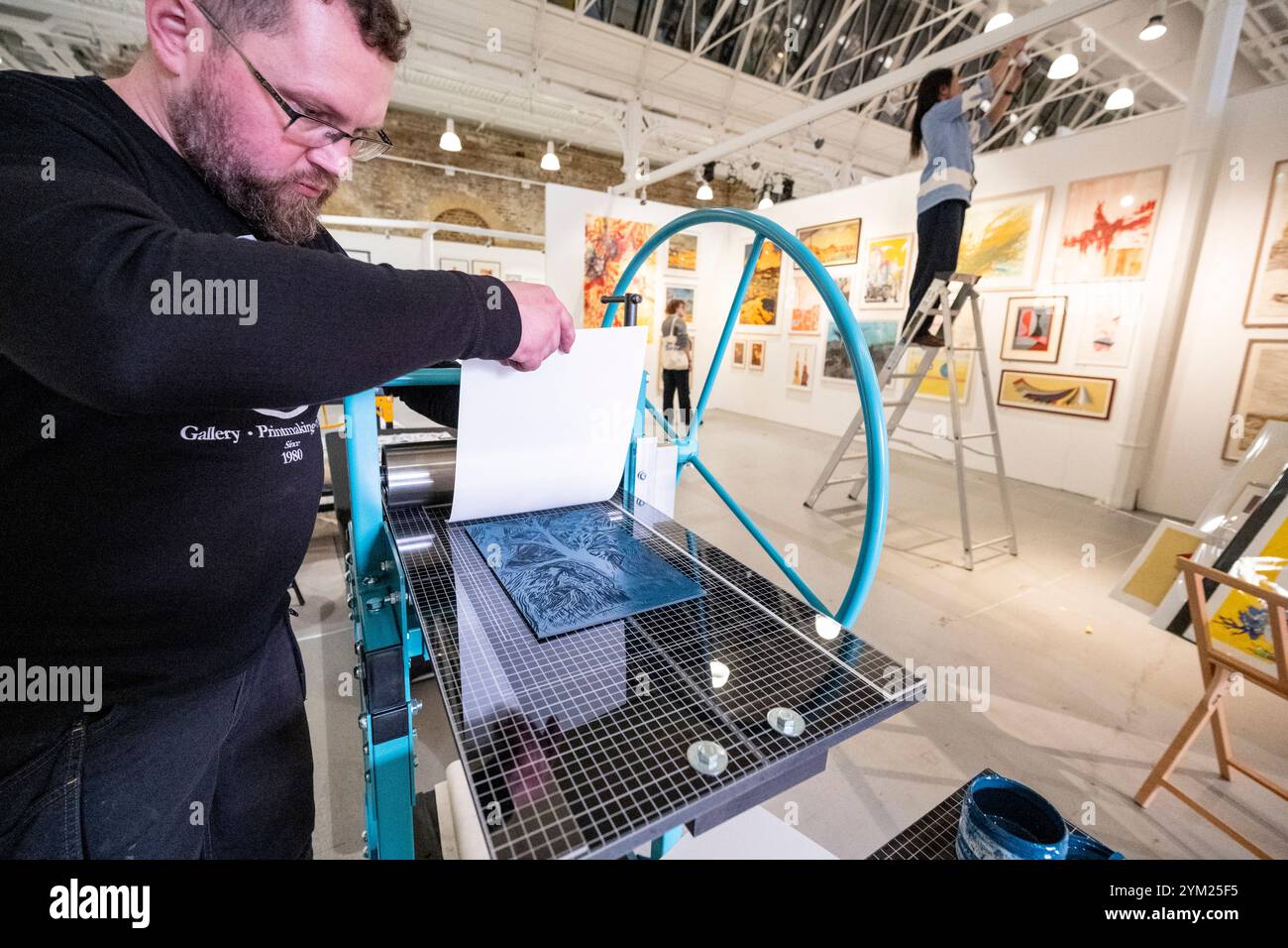 Londres, Royaume-Uni. 20 novembre 2024. Le graveur Dave Mason-Gunning d'Ironbridge Fine Arts fait une démonstration de sa presse à imprimer lors d'une avant-première de Woolwich Contemporary Print Fair qui présente des artistes émergents et établis et le médium de la gravure. Des estampes contemporaines originales de plus de 1000 artistes et galeries de premier plan sont présentées dans le salon à Woolwich Works, au sud-est de Londres, du 21 au 24 novembre. Credit : Stephen Chung / Alamy Live News Banque D'Images