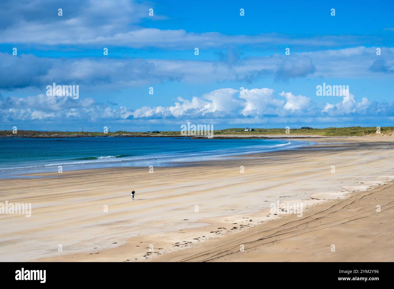 Une figure solitaire traverse les sables dorés de la plage de Crossapol sur l'île de Coll, dans les Hébrides intérieures, en Écosse, au Royaume-Uni Banque D'Images