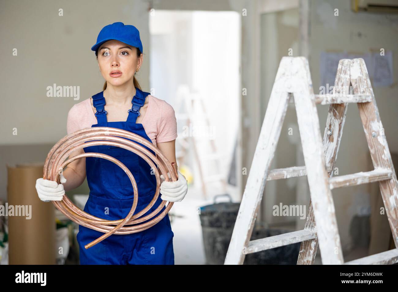 Portrait de femme constructeur dans des combinaisons bleues avec des tubes de chauffage au sol dans les mains Banque D'Images