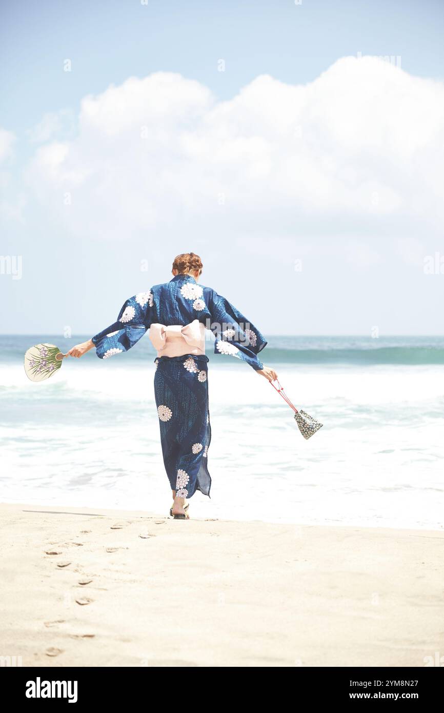 Femme en kimono marchant sur la plage Banque D'Images