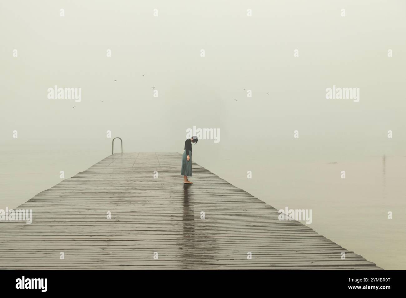 femme solitaire avec la tête en bas sur une jetée surplombant la mer d'hiver Banque D'Images