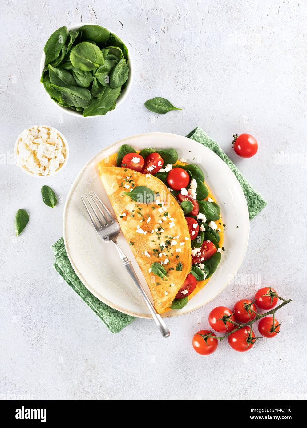 Omelette farcie avec tomates, fromage et épinards sur fond blanc. Vue de dessus. Banque D'Images