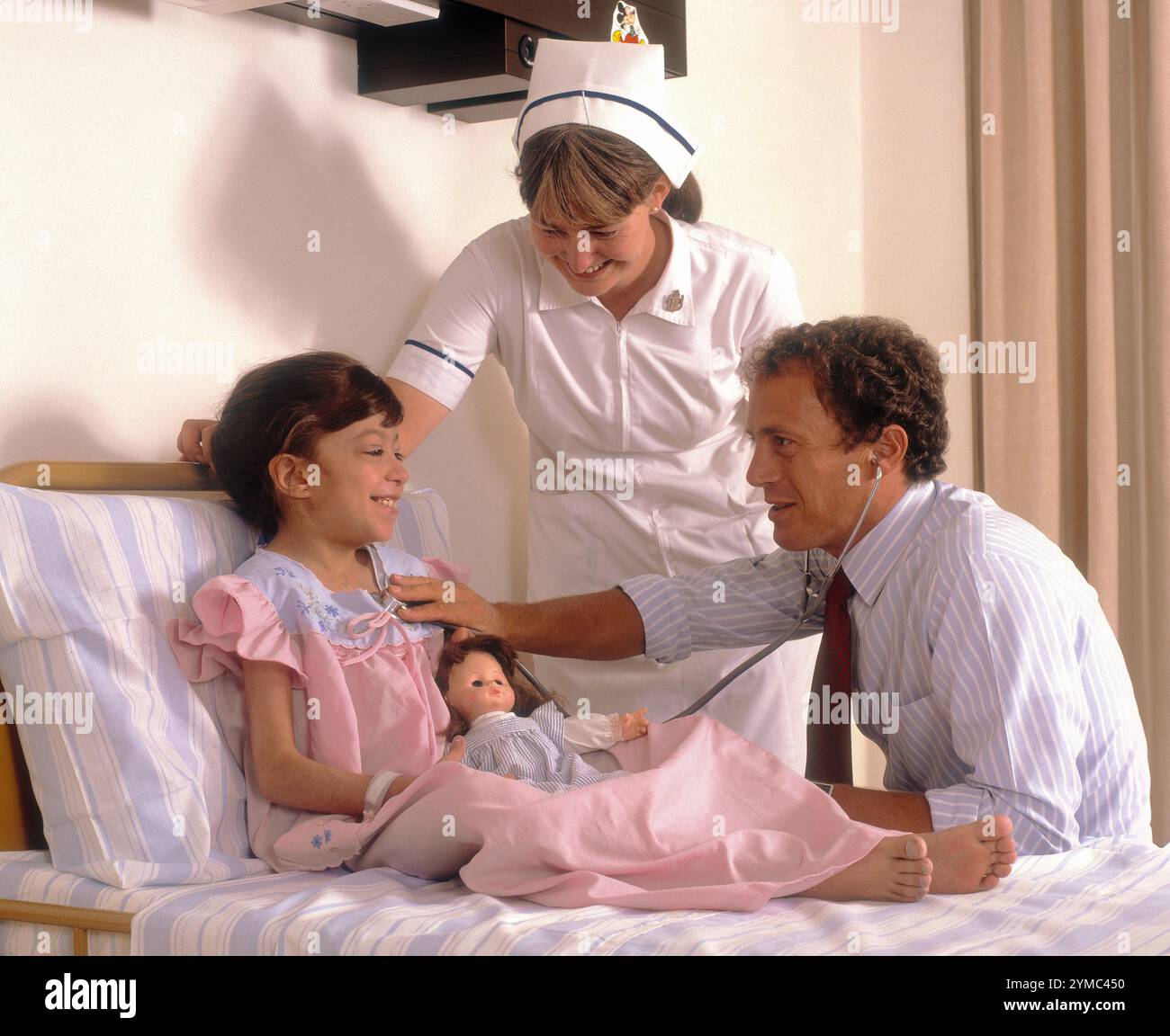 Une charmante photo d'un jeune enfant, médecin et infirmière à l'hôpital Ibn al-bitar dans le district de Karkh à Bagdad, en Irak. Au moment du tournage, vers 1985, l'hôpital était géré par PARC, une filiale d'Aer Lingus, pour le compte du gouvernement irakien. Il a fourni aux citoyens iraquiens un niveau élevé de soins, y compris des greffes et des chirurgies cardiaques, ainsi que d'autres procédures complexes. Des centaines de membres du personnel irlandais y travaillèrent dans tous les domaines d'activité, dont certains furent piégés à Bagdad pendant la première guerre du Golfe en 1991, ce qui mit fin à l'implication irlandaise. Banque D'Images