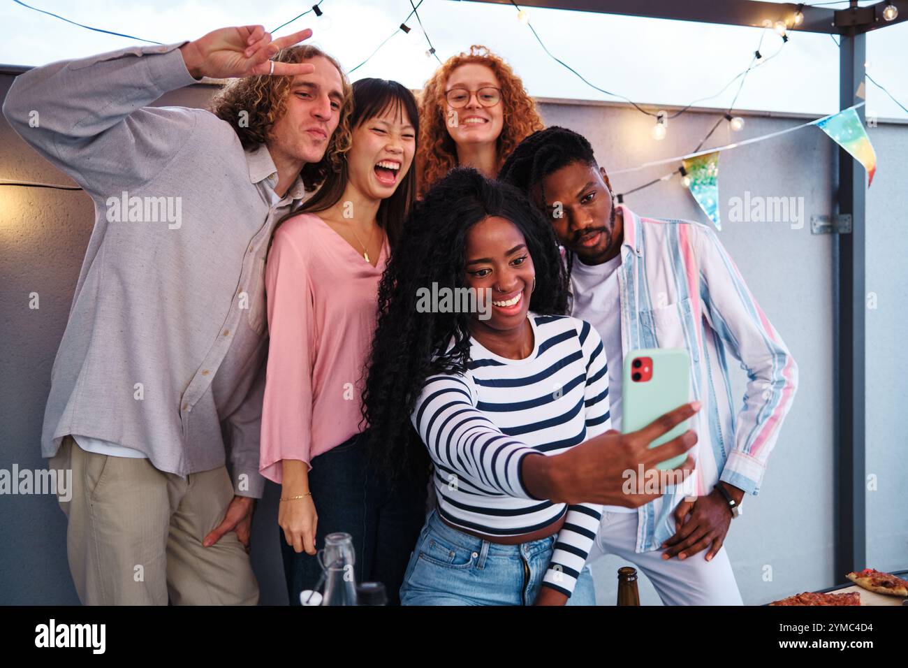 Amis multiethniques prenant selfie à la fête sur le toit Banque D'Images