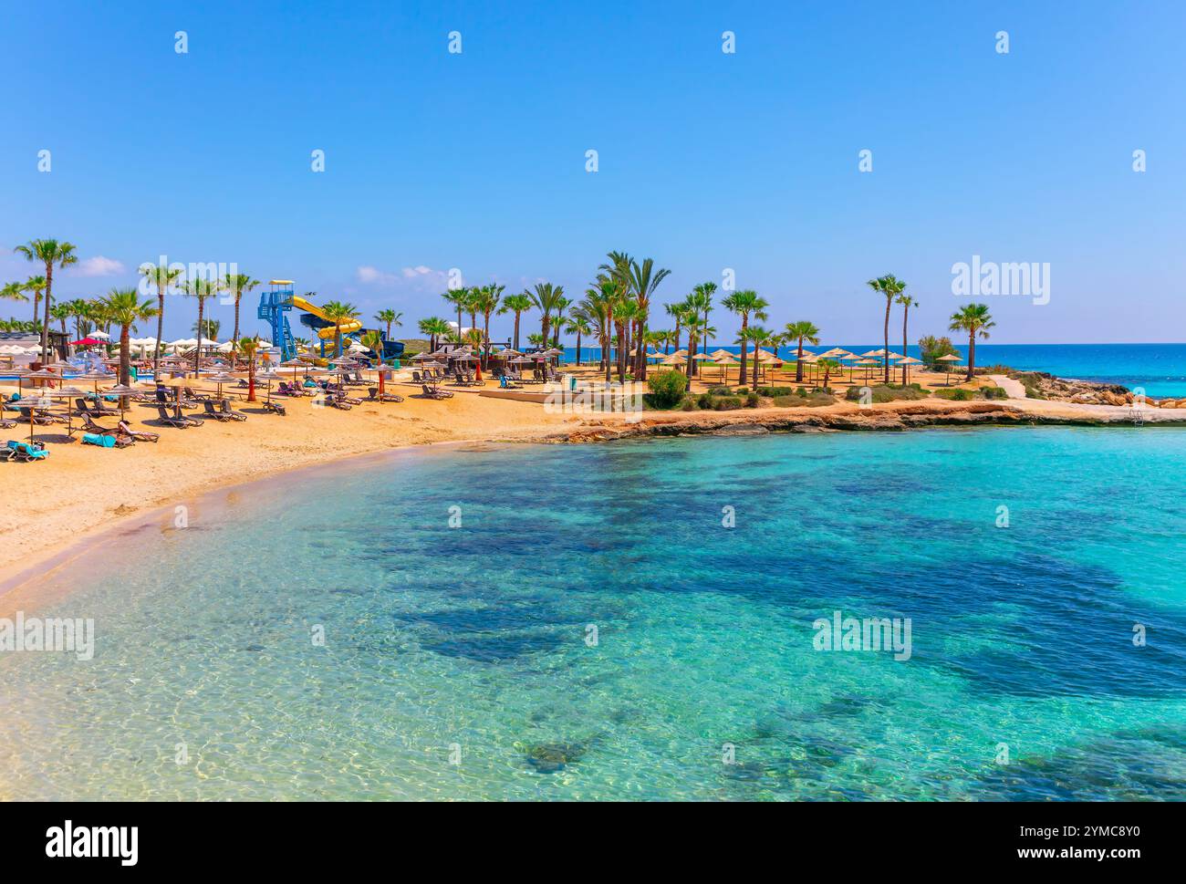 Ayia Napa, Chypre avec ses plages de sable doré et ses eaux turquoises, ses palmiers et ses chaises longues, crée un paradis tropical. Parfait pour la détente, Wit Banque D'Images
